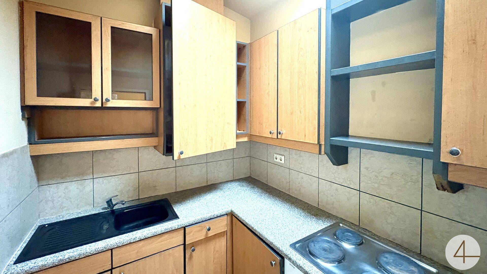 Kleine Küche mit Holzschränken, Fliesenrückwand und Elektroherd.