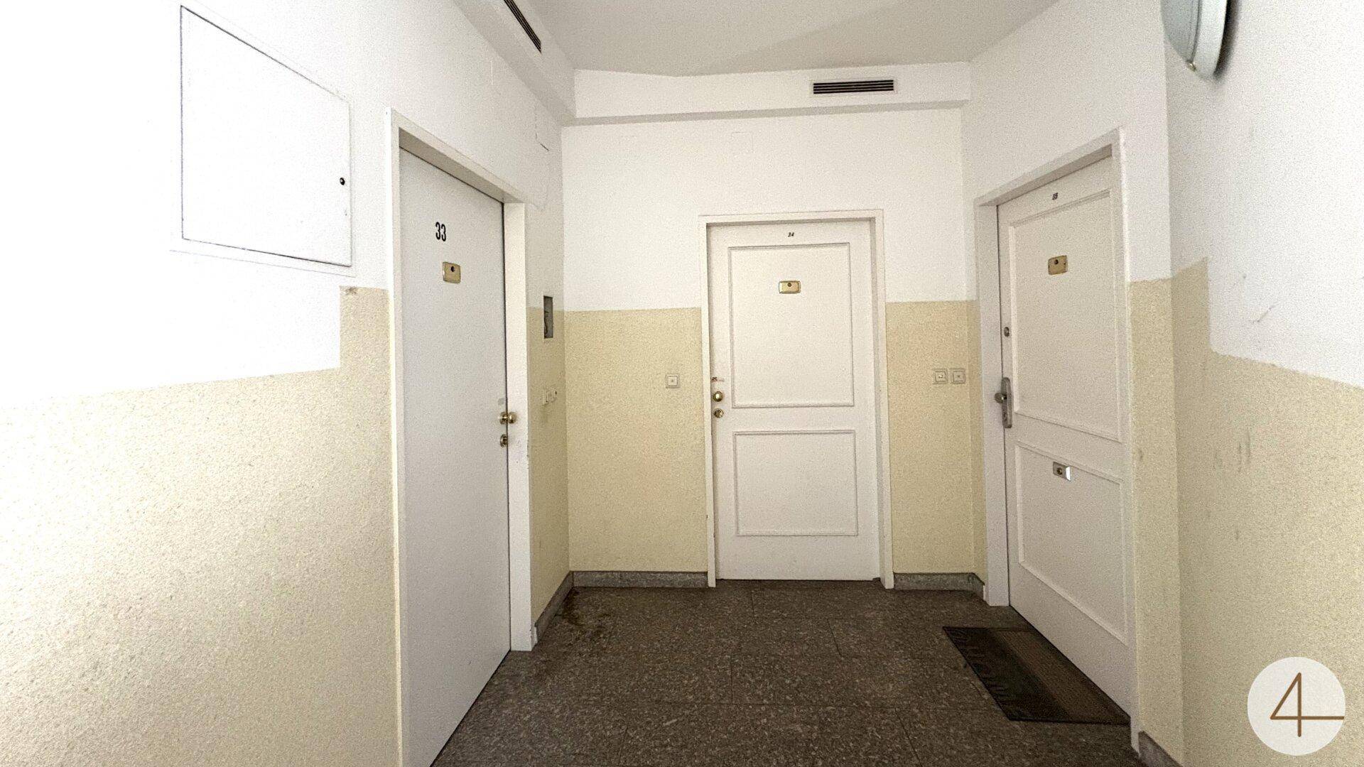 Gemeinschaftsflur mit mehreren Wohnungstüren und Terrazzoboden.