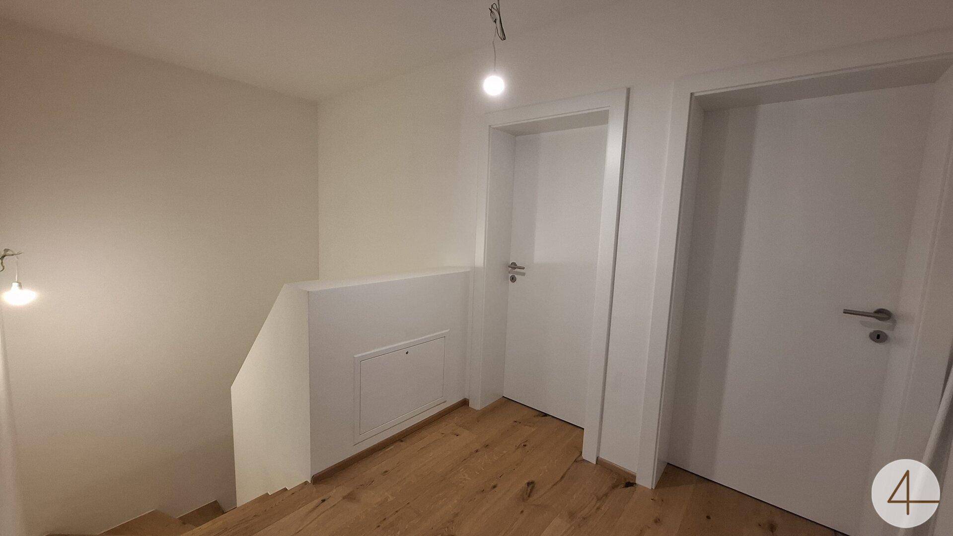 Flur mit Holzboden und Zugang zu den oberen Etagen und weiteren Zimmern.