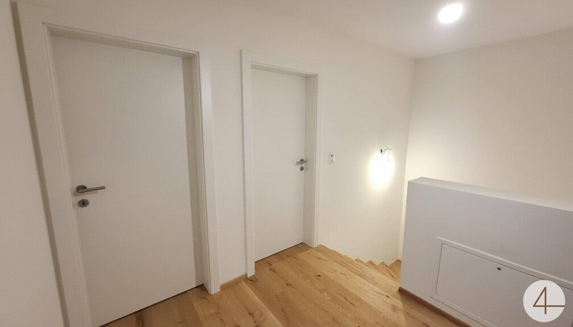Heller Flur mit Holzboden und Türen zu den angrenzenden Räumen im Obergeschoss.