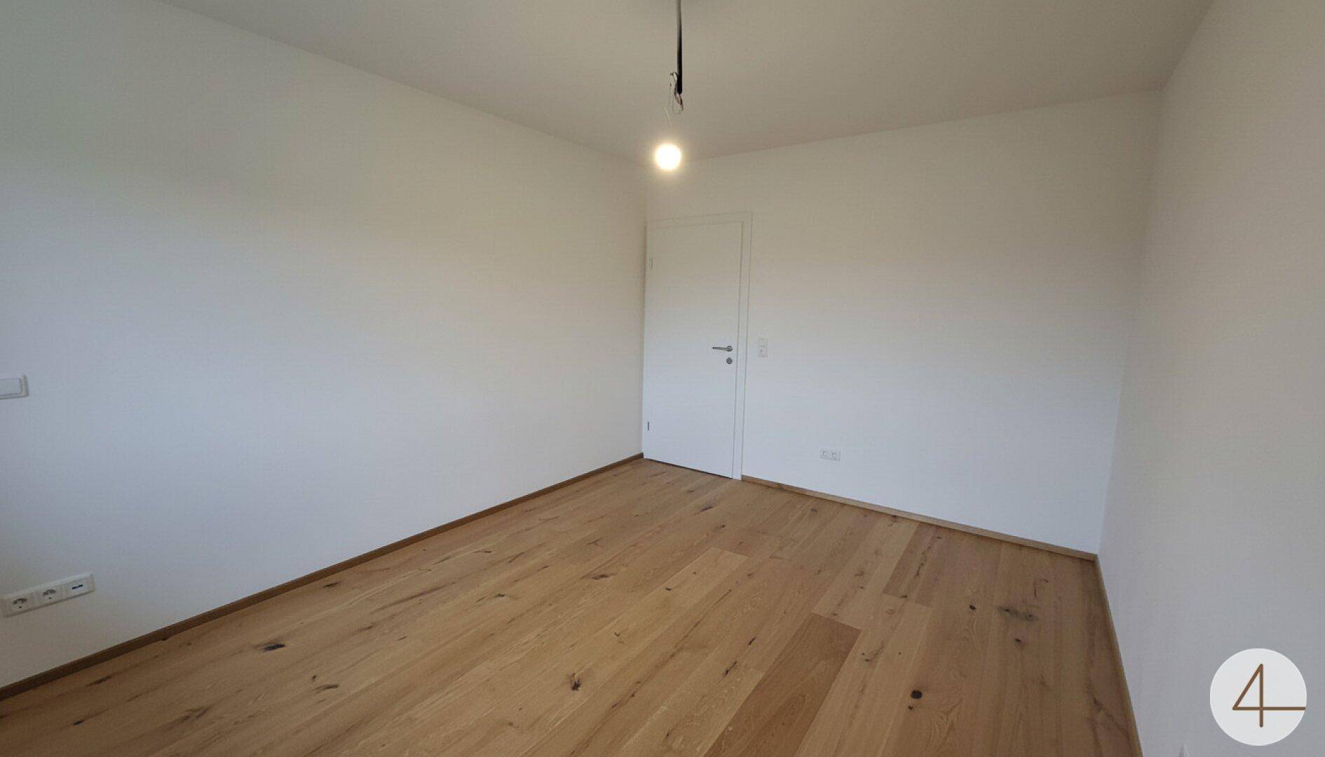 Unmöbliertes Schlafzimmer mit Holzboden und hellen Wänden, bereit zum Einzug.
