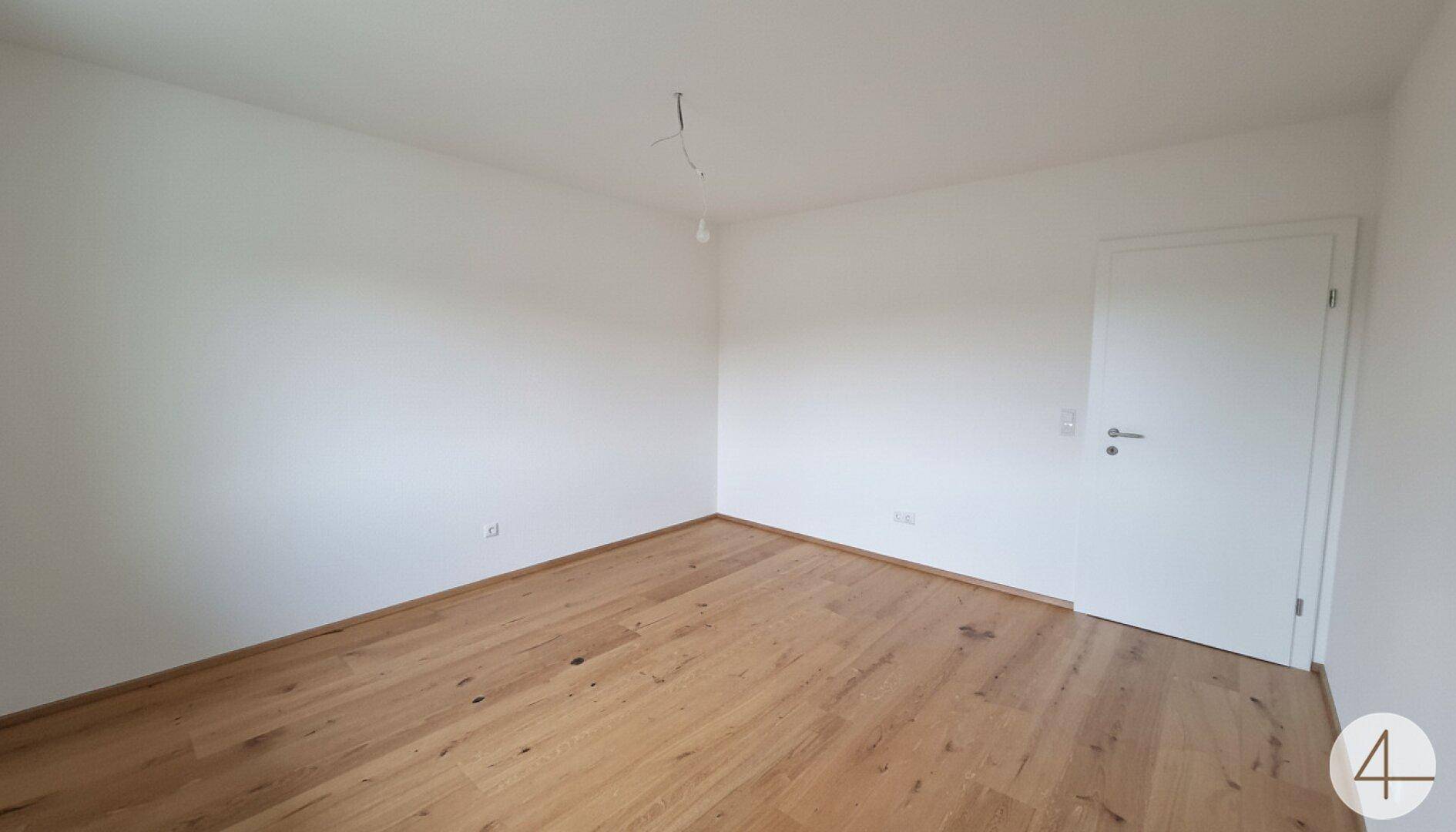 Leeres Schlafzimmer mit Holzboden und weißen Wänden, ideal für individuelle Einrichtung.