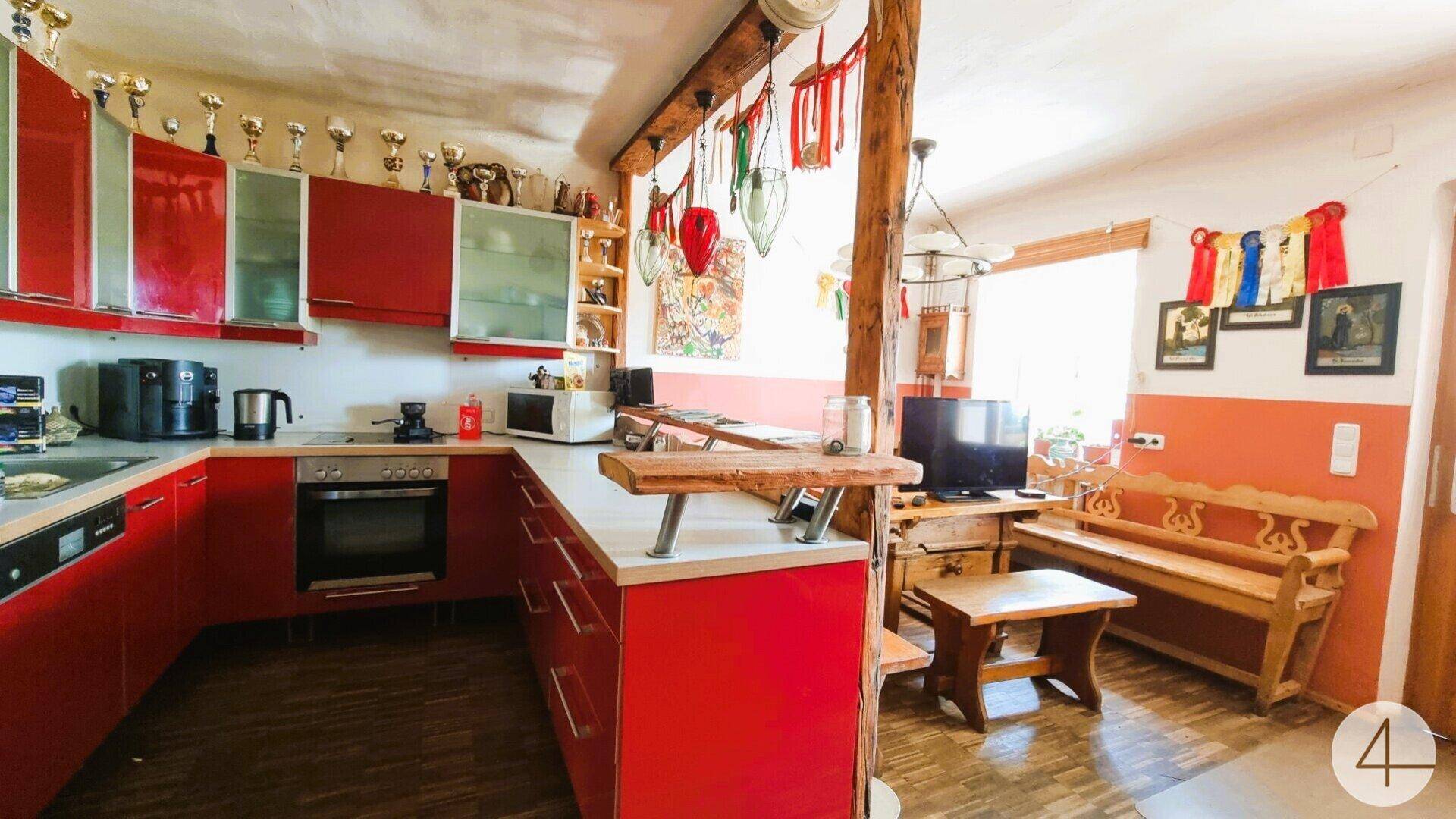 Auffällige rote Küche mit integriertem Essbereich, Holzarbeitsplatten und traditionellen Elementen.