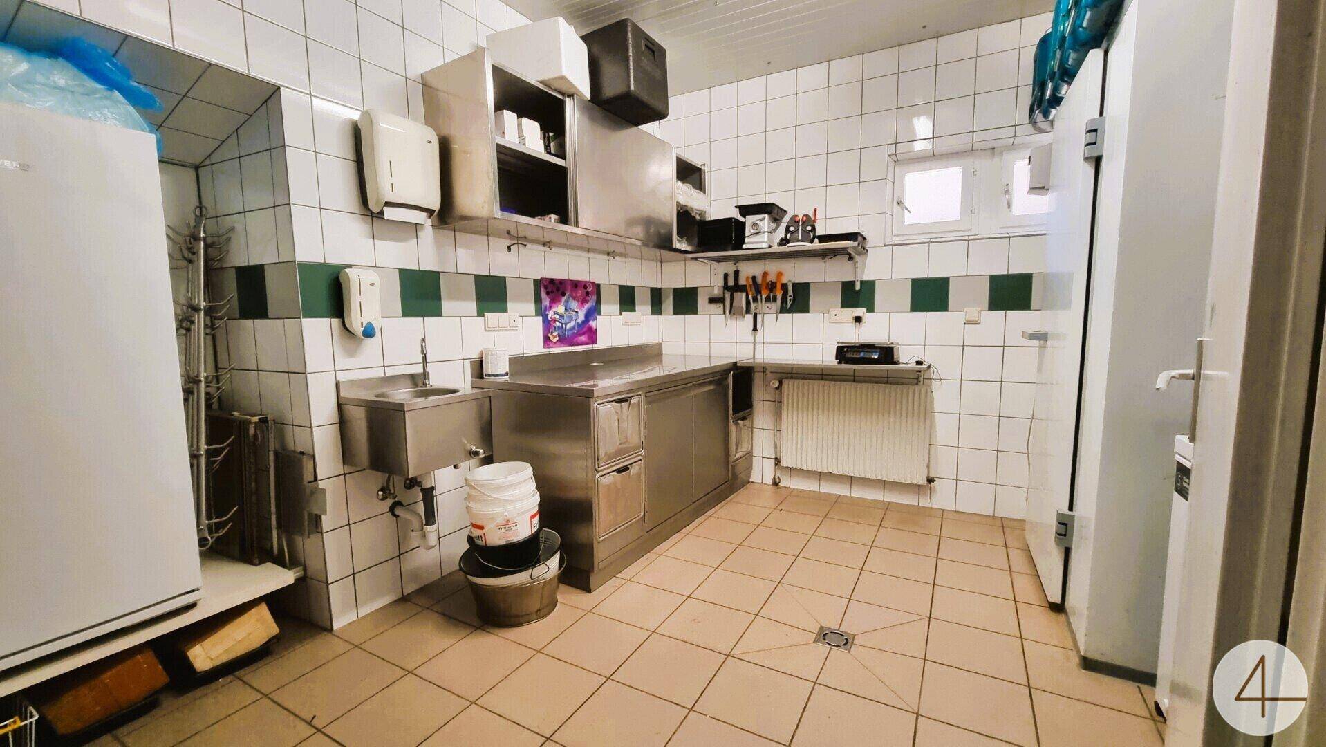 Professionelle Gewerbeküche mit Edelstahlgeräten, Fliesenwänden und -boden, funktional und sauber.