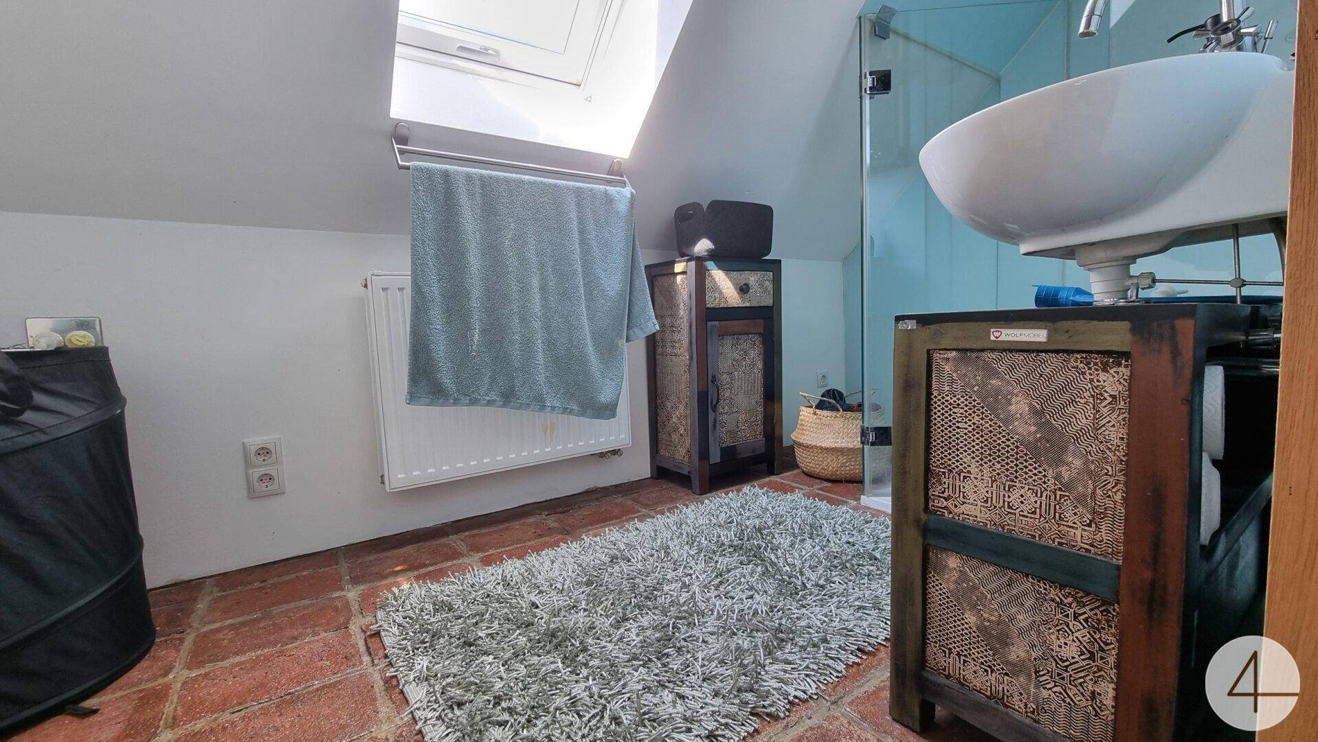 Helles Badezimmer mit Dachschräge, Dachfenster, Dusche und Terrakottafliesen, im Landhausstil.