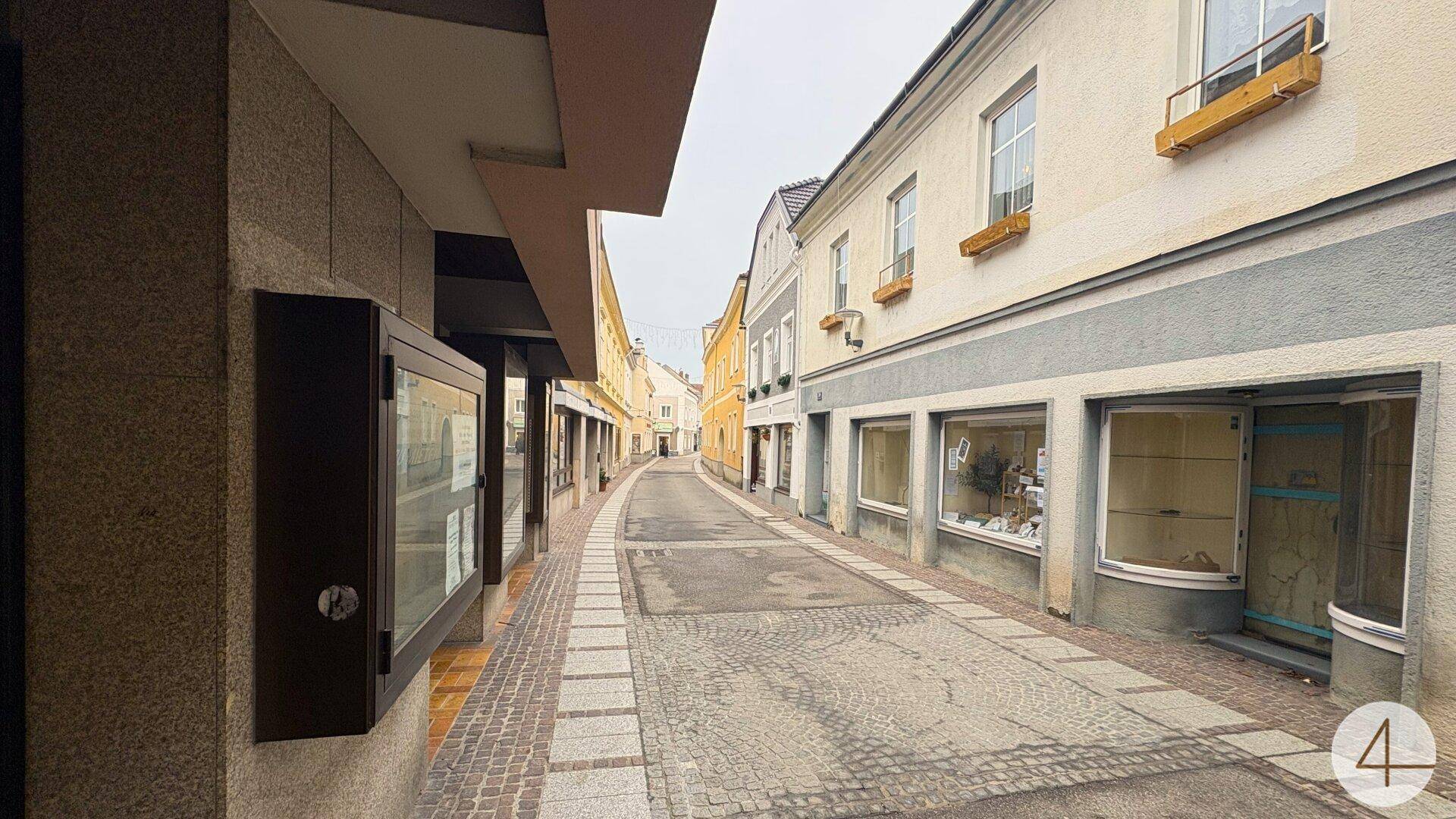 Enge Gasse mit Kopfsteinpflaster und Geschäften in historischen Gebäuden einer Altstadt.