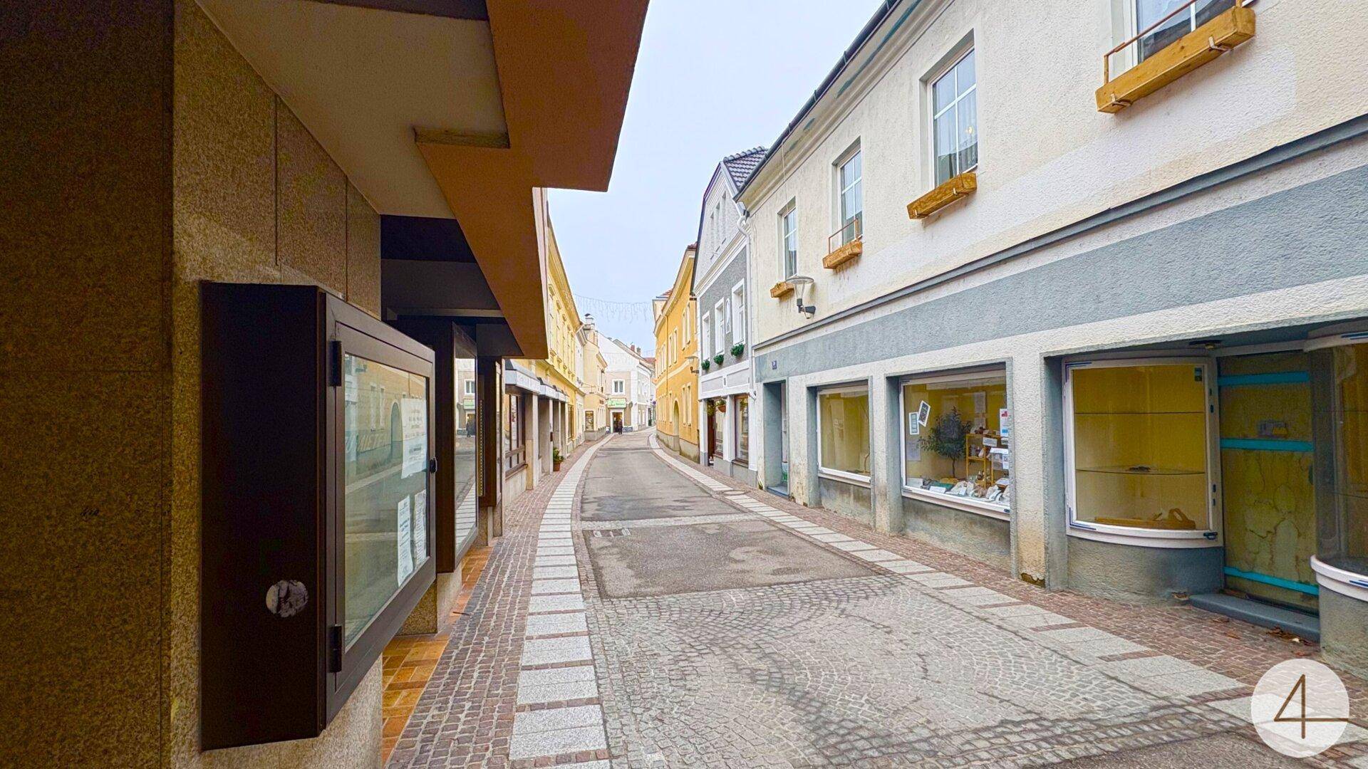 Enge Gasse mit Kopfsteinpflaster und Geschäften in historischen Gebäuden einer Altstadt.