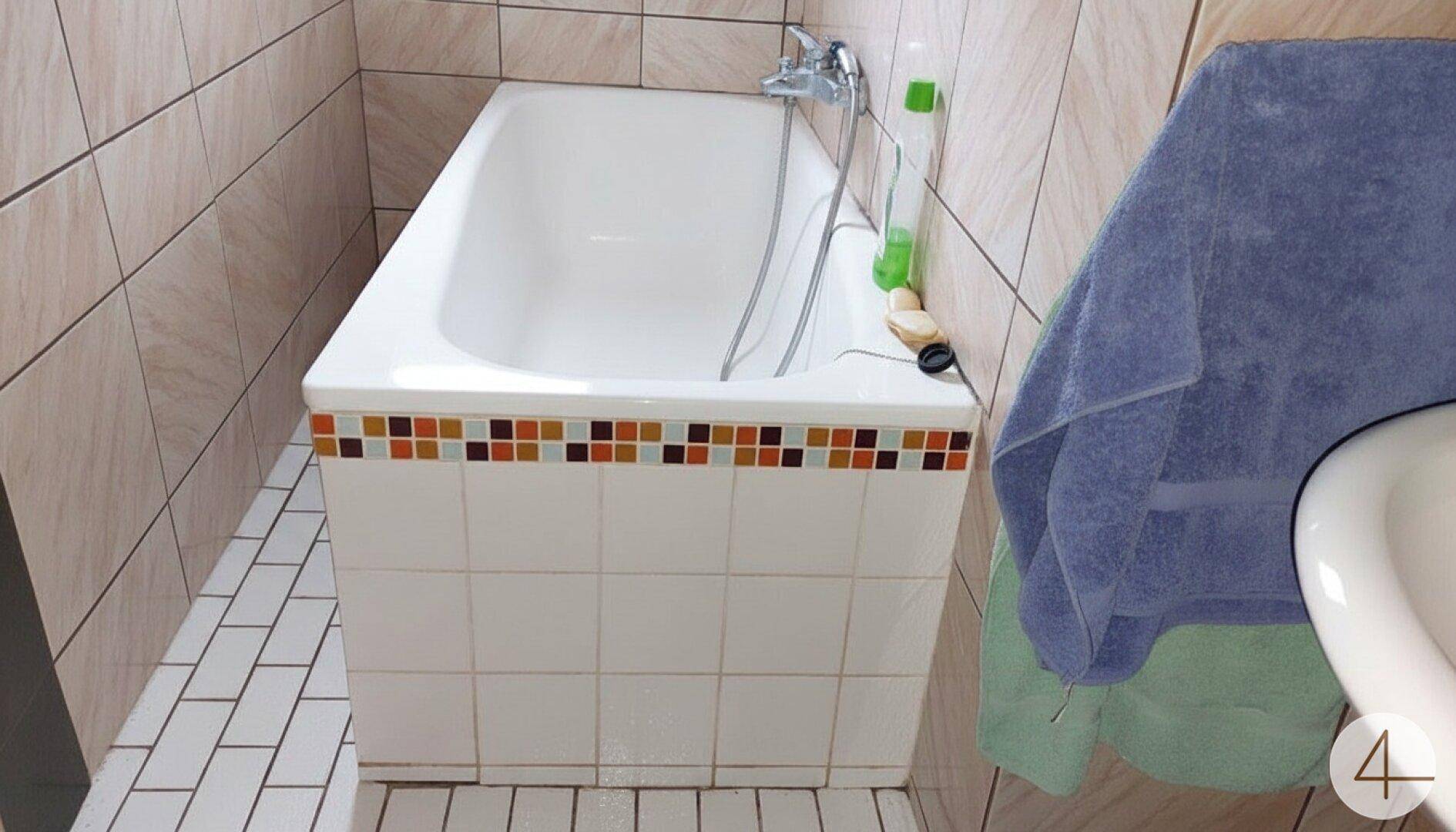 Badezimmer mit Badewanne und Fliesen in warmen Farbtönen, die einen klassischen Stil zeigen.