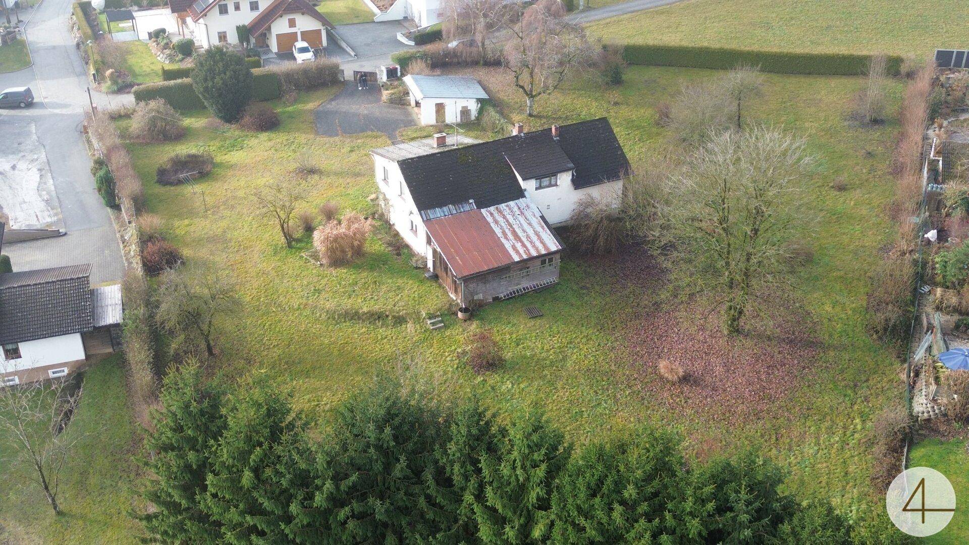 Luftaufnahme eines älteren Hauses mit großem Grundstück und angrenzenden Feldern in ländlicher Umgebung.