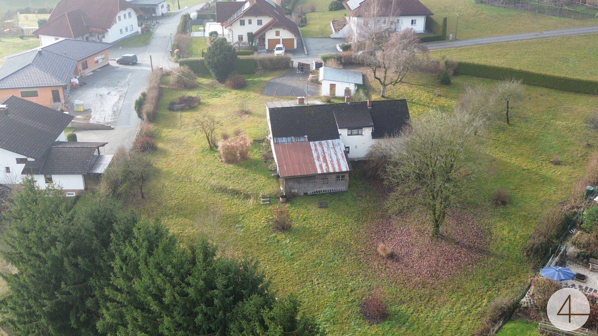 Weitläufige Ansicht des Anwesens von oben, umgeben von Grünflächen und weiteren Wohnhäusern.