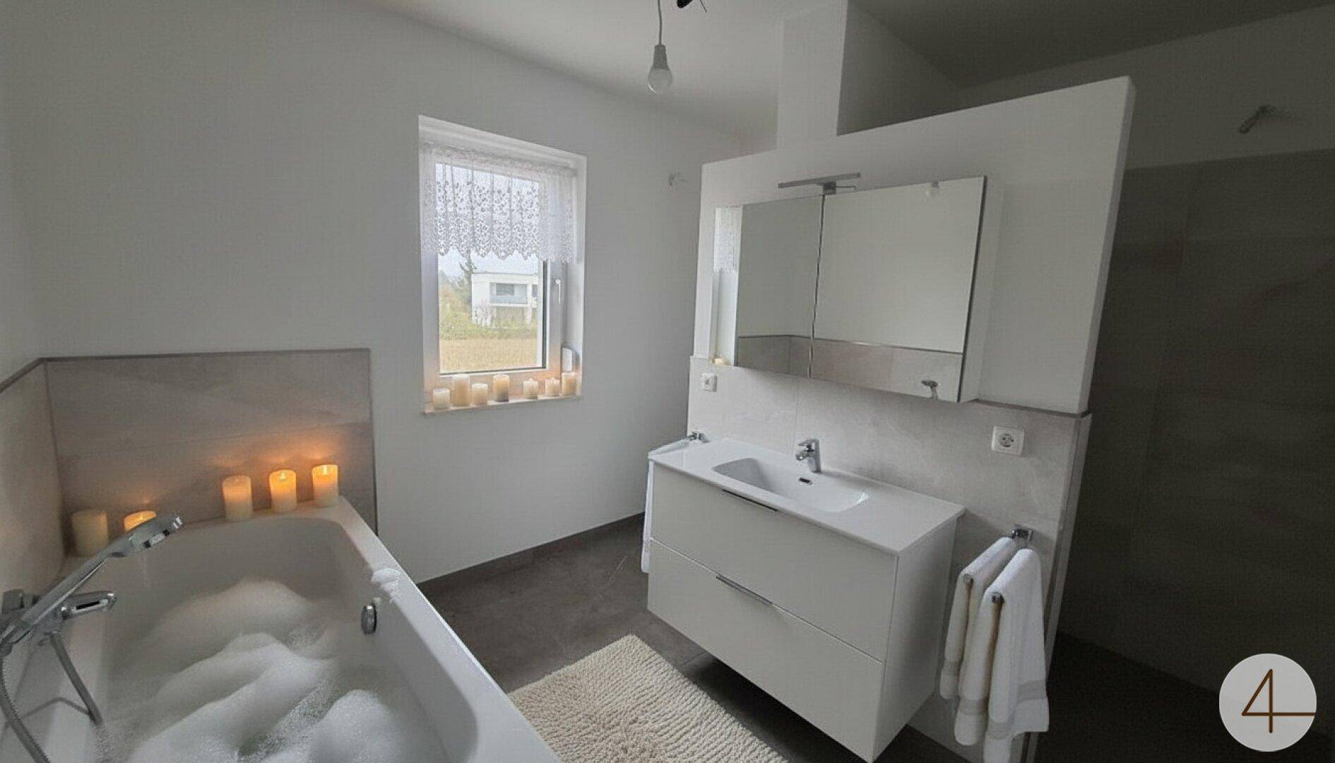 Modernes Badezimmer mit Badewanne, Einzelwaschbecken, Spiegelschrank und Fenster.