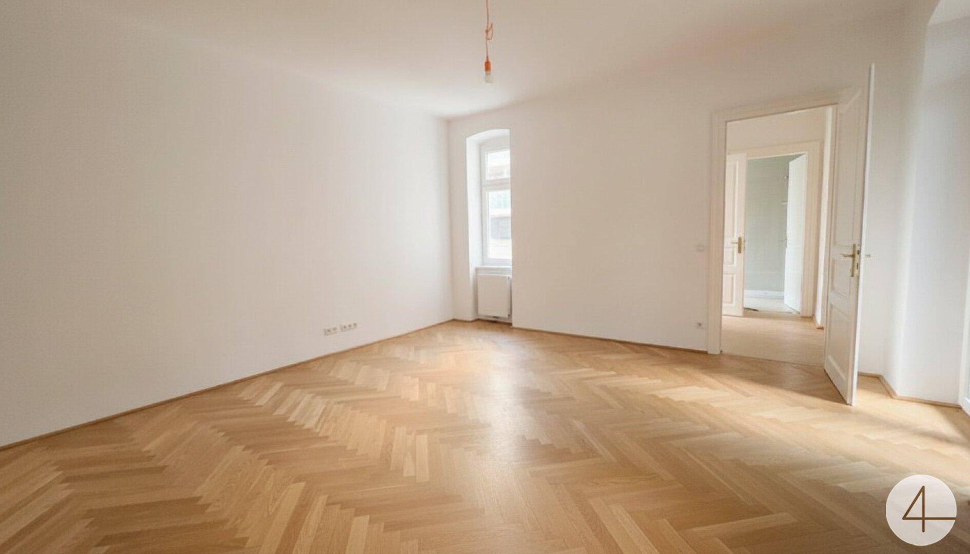 Geräumiger, heller Raum mit Fischgrätparkett und hohen Decken, ideal für Wohnzwecke.