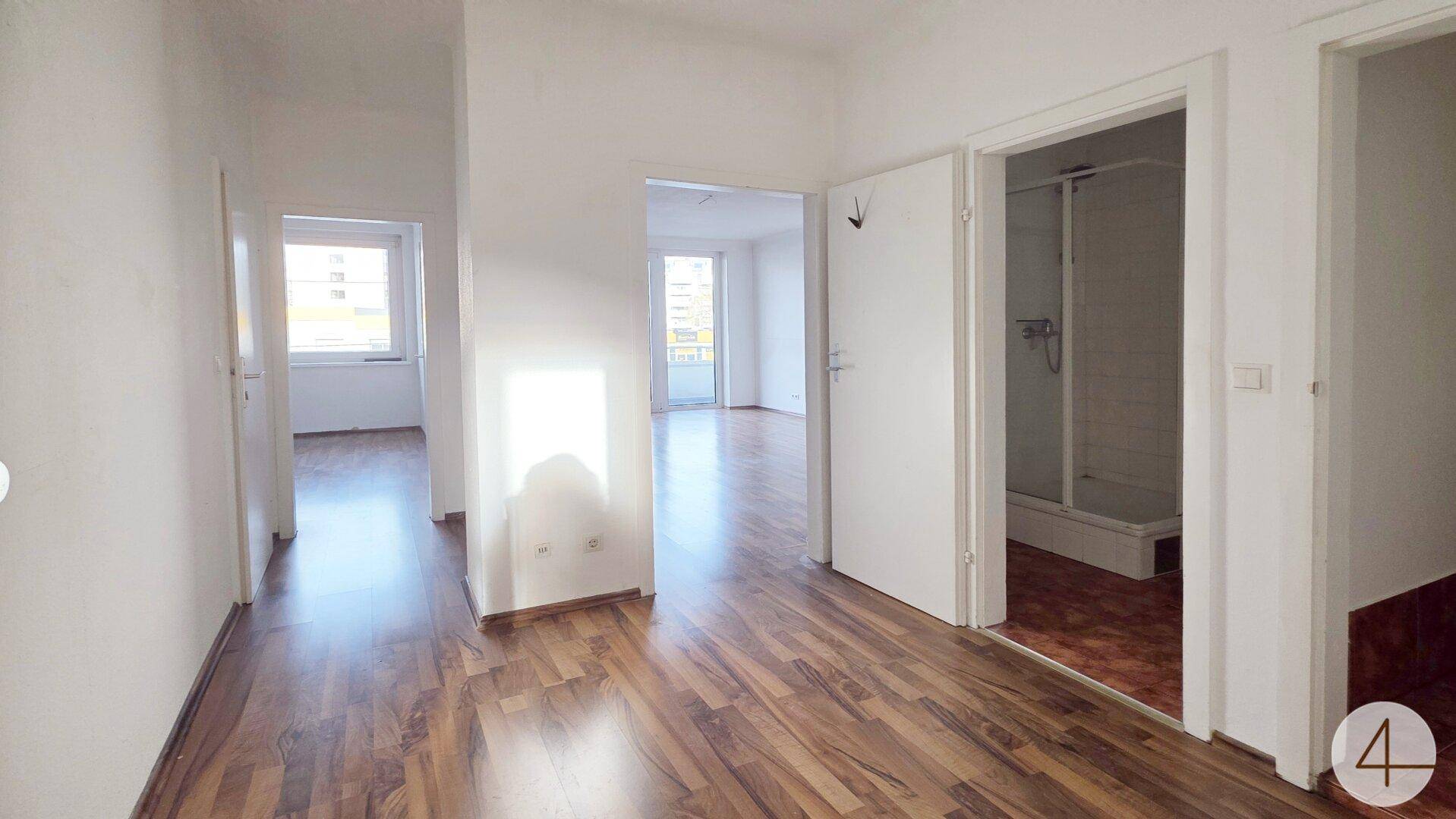 Heller Flur mit Laminatboden, der zu verschiedenen Zimmern und dem Badezimmer führt.