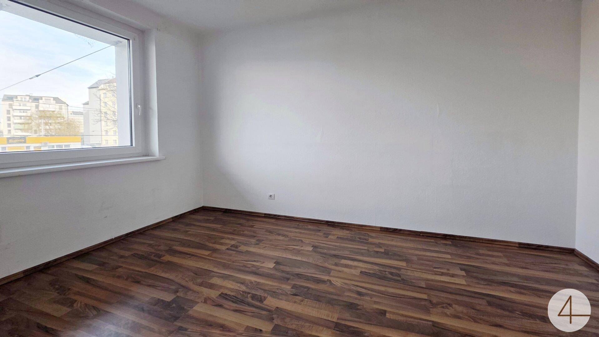 Helles Schlafzimmer mit Laminatboden und großem Fenster, das eine angenehme Wohnatmosphäre schafft.