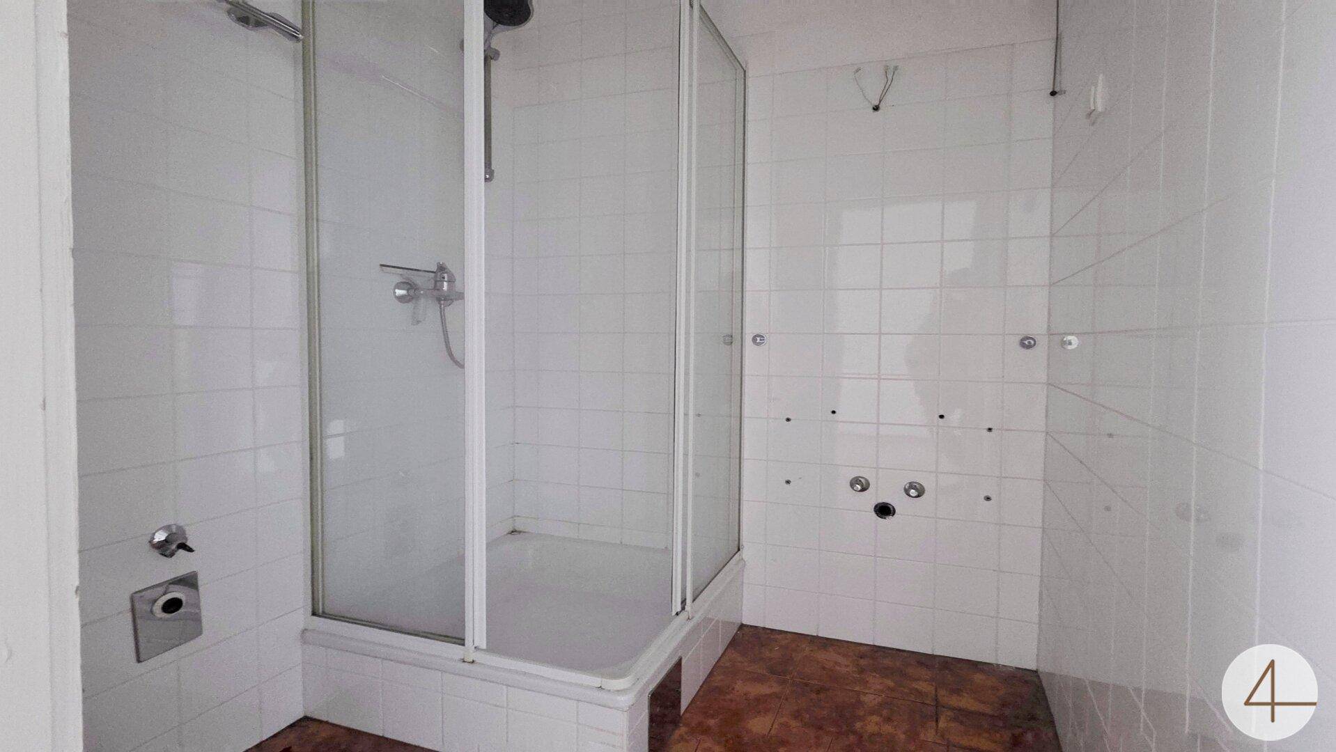 Badezimmer mit Duschkabine und weißen Fliesen, bereit für die Installation neuer Armaturen und Möbel.