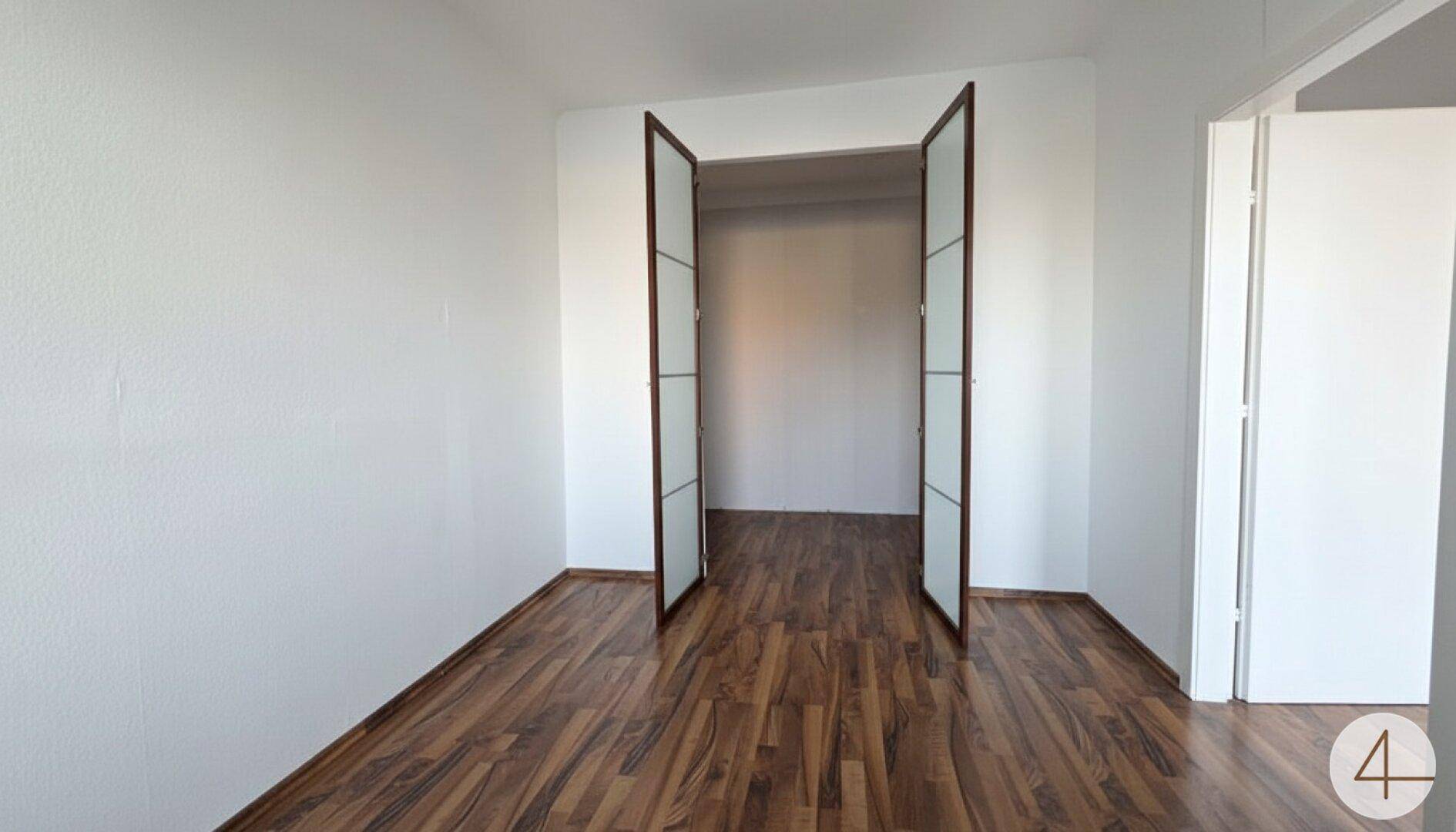 Helles Zimmer mit Laminatboden und Doppeltüren, das vielseitig als Schlaf- oder Arbeitszimmer genutzt werden kann.