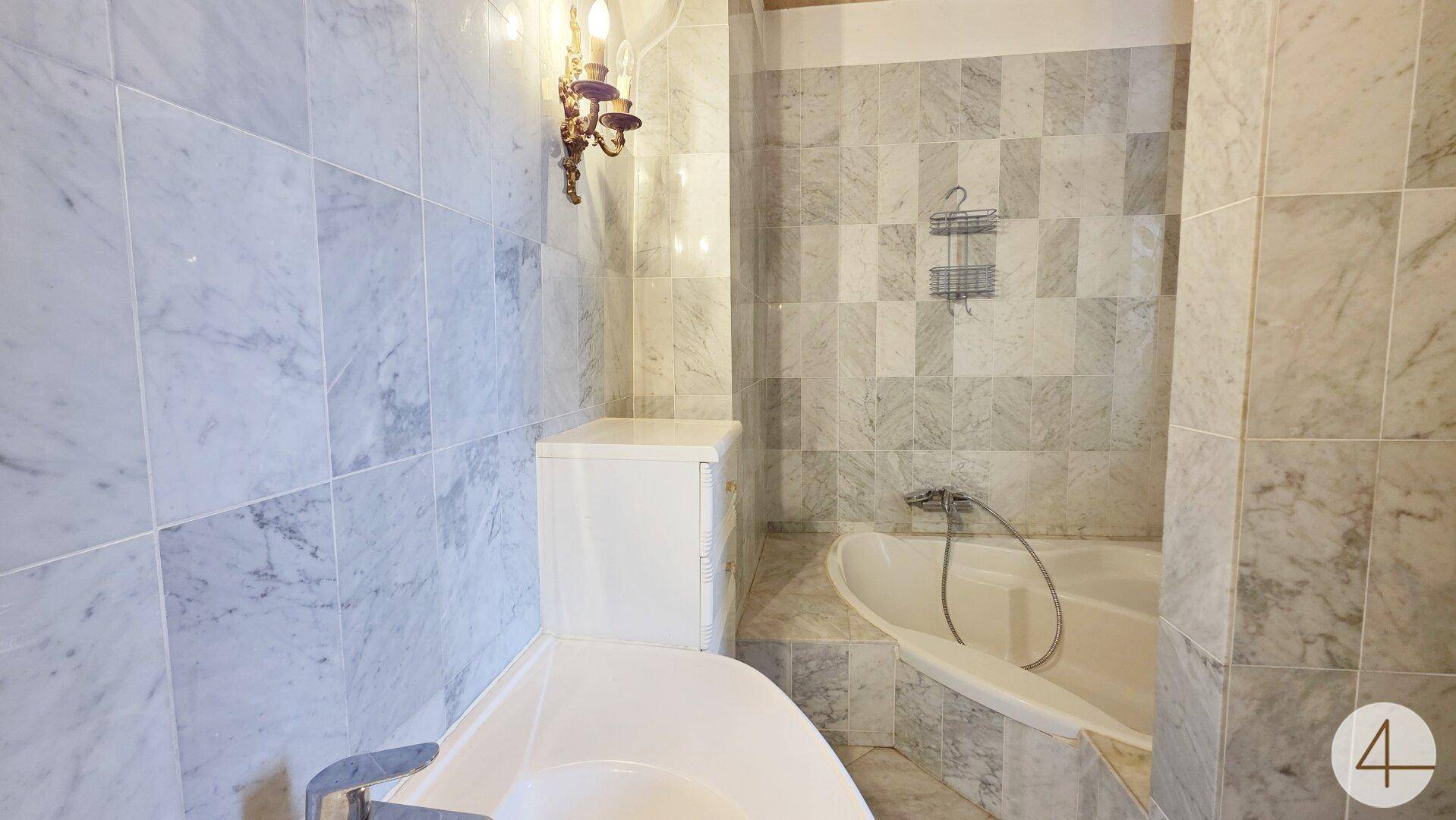 Detailansicht der Badewanne und der hochwertigen Marmorfliesen im Badezimmer.