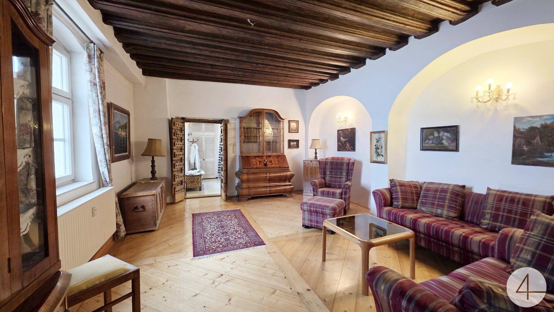 Gemütliches Wohnzimmer mit karierten Sofas, antiken Möbeln und Holzbalkendecke im Altbaustil.
