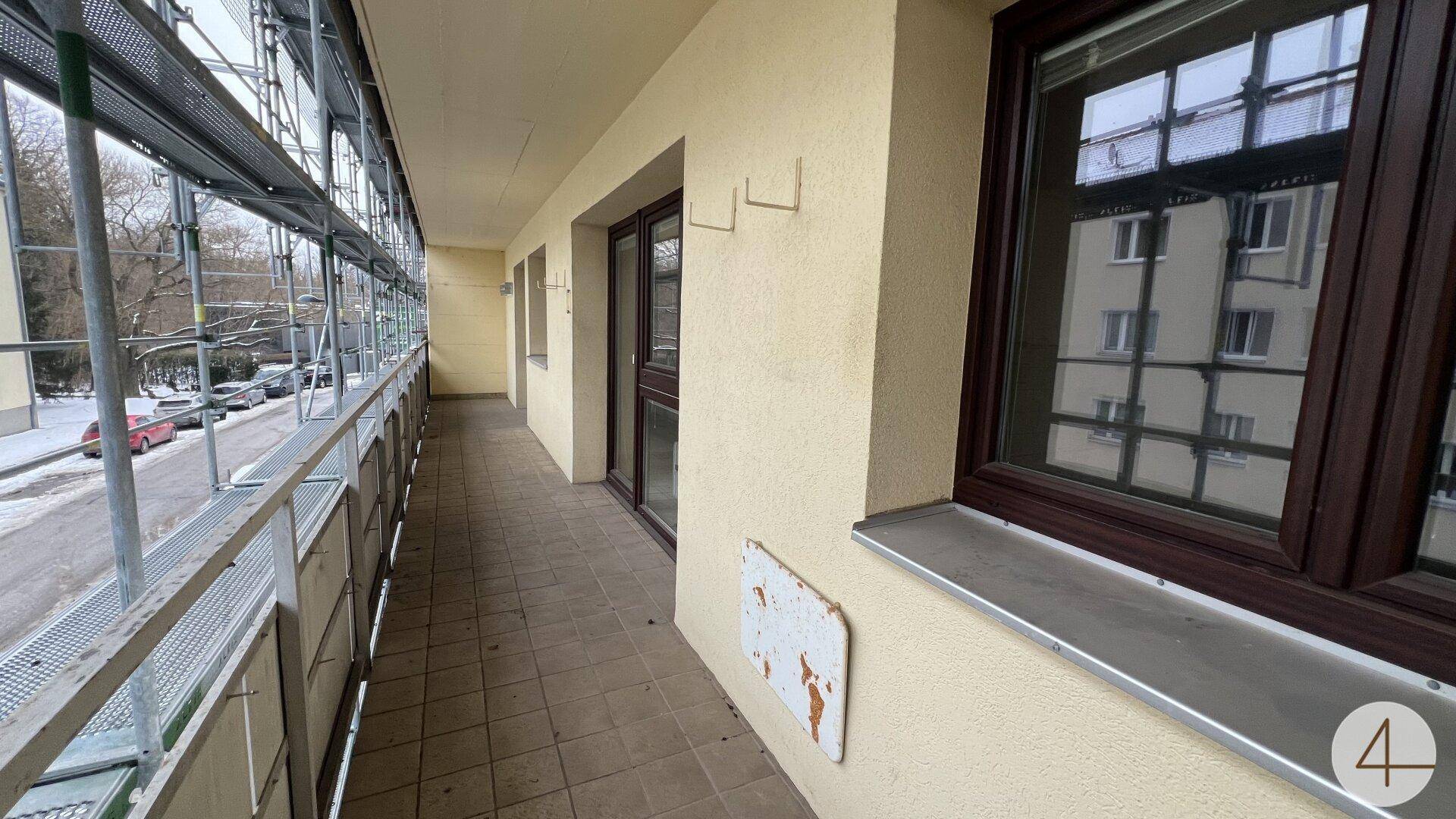 Langer Balkon mit Blick auf die Straße, derzeit mit Baugerüst versehen.