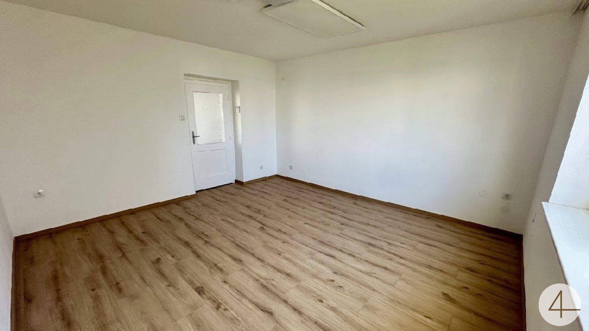 Heller Raum mit Laminatboden und weißer Tür, ideal als Schlaf- oder Arbeitszimmer.