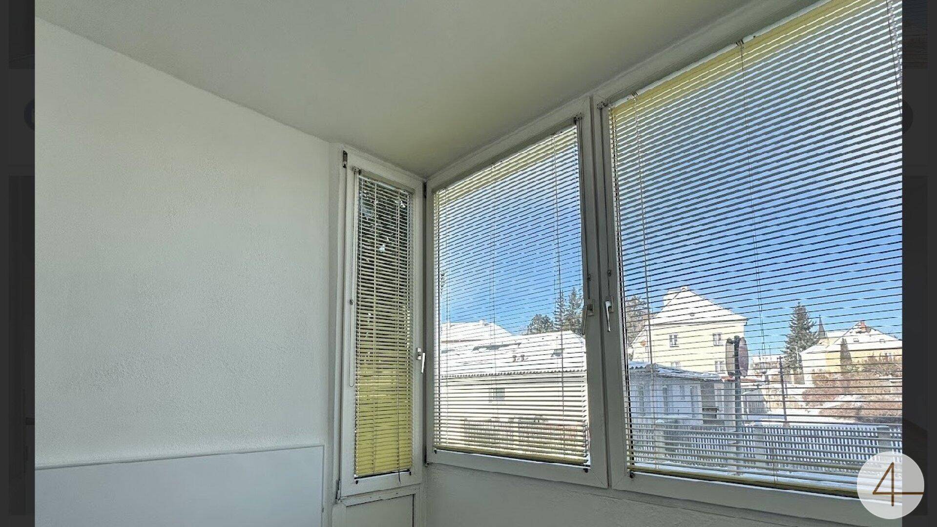 Verglaster Balkon mit weitem Blick auf die umliegenden Gebäude und den Himmel.