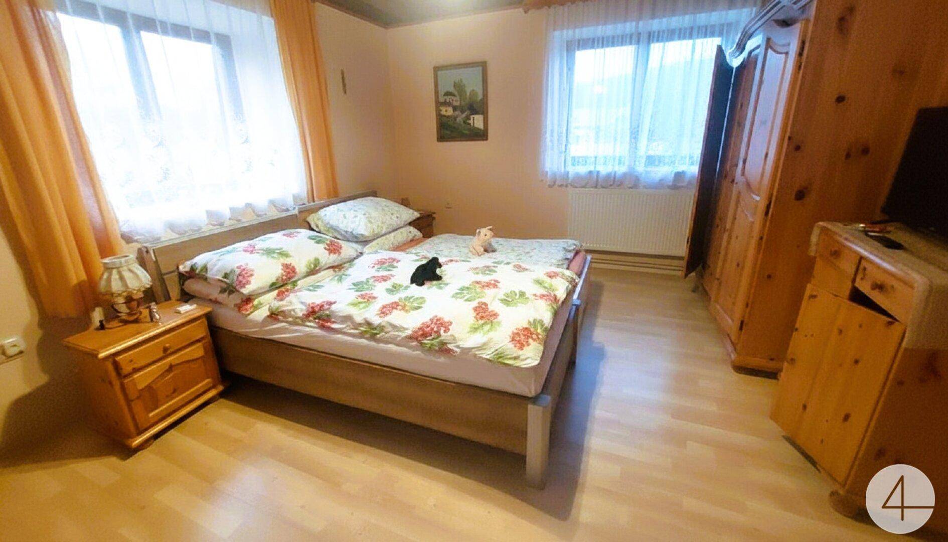 Gemütliches Schlafzimmer mit Holzmöbeln, Doppelbett und Blick aus dem Fenster.