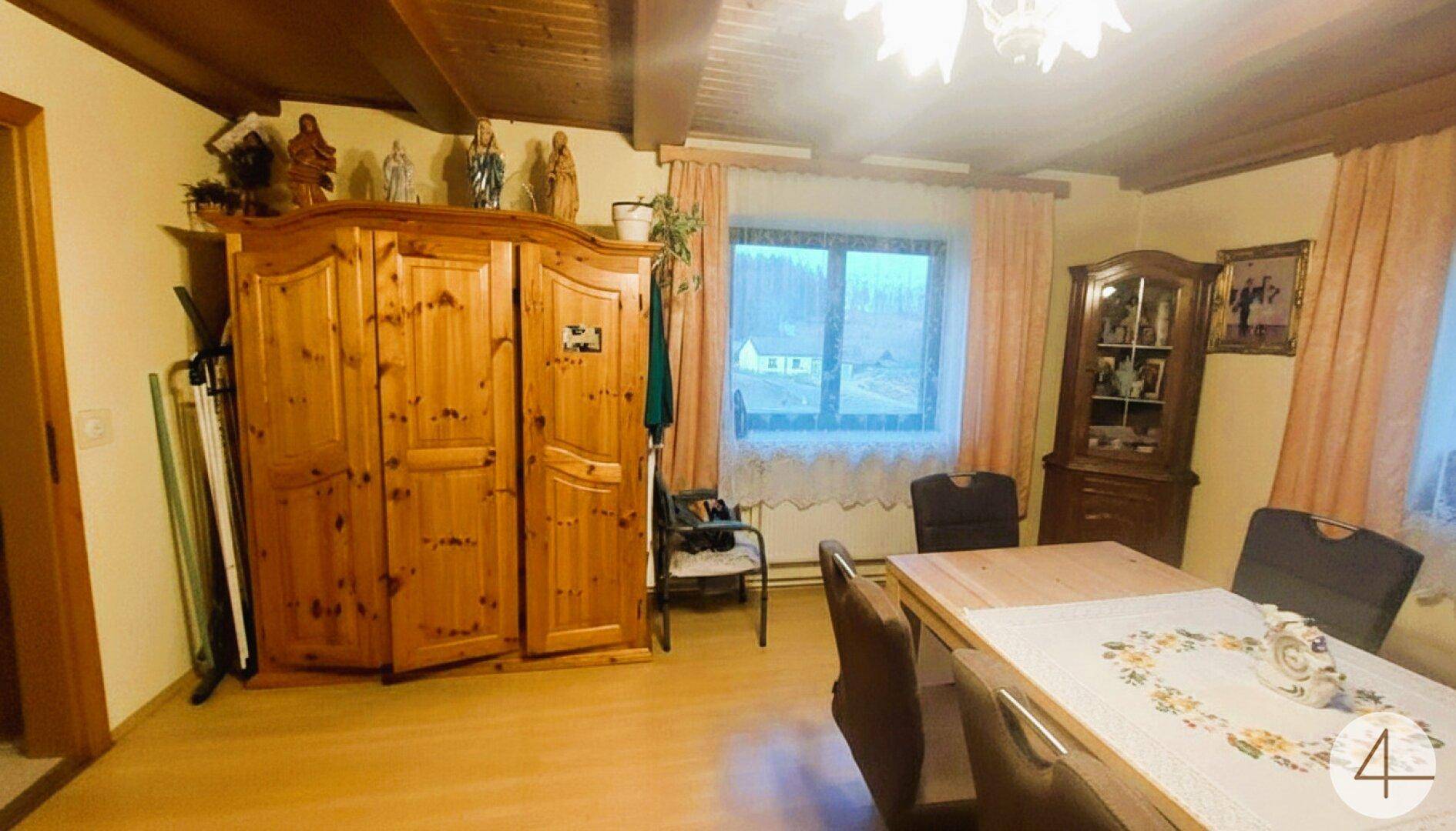 Traditioneller Essbereich mit Holzschrank, Esstisch und Blick auf die ländliche Umgebung.
