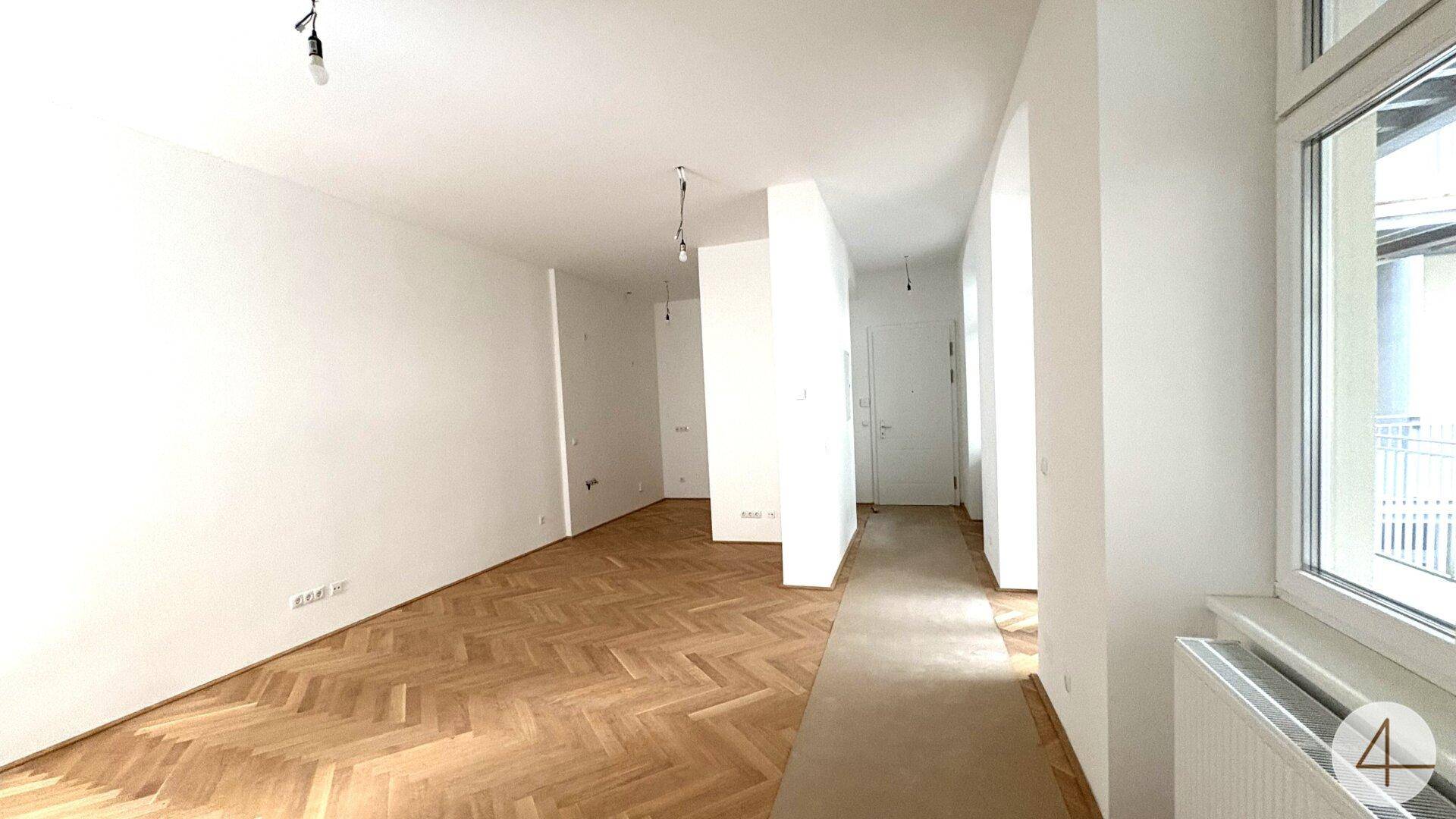 Langer, heller Flur mit Fischgrätparkett, der zu den verschiedenen Räumen der Wohnung führt.
