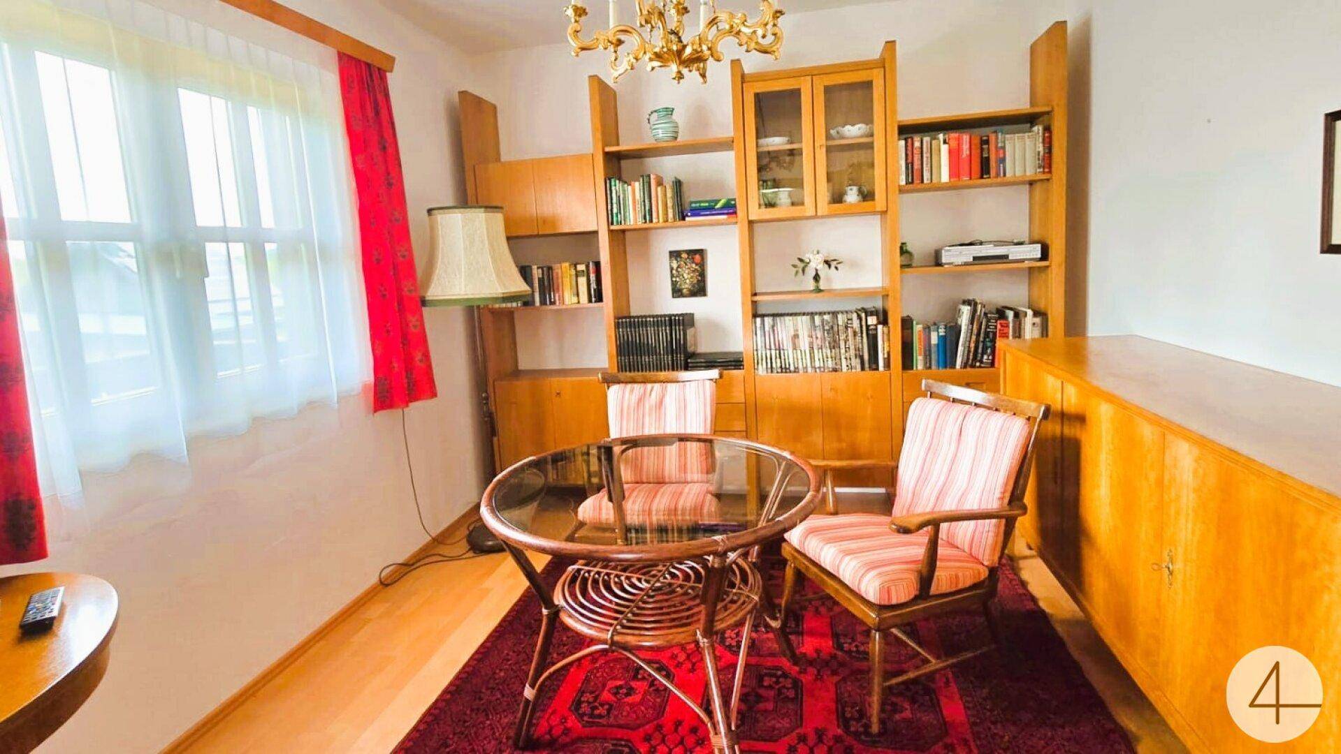 Gemütlicher Wohnbereich mit Bücherregal, kleinem Tisch und traditioneller Einrichtung.