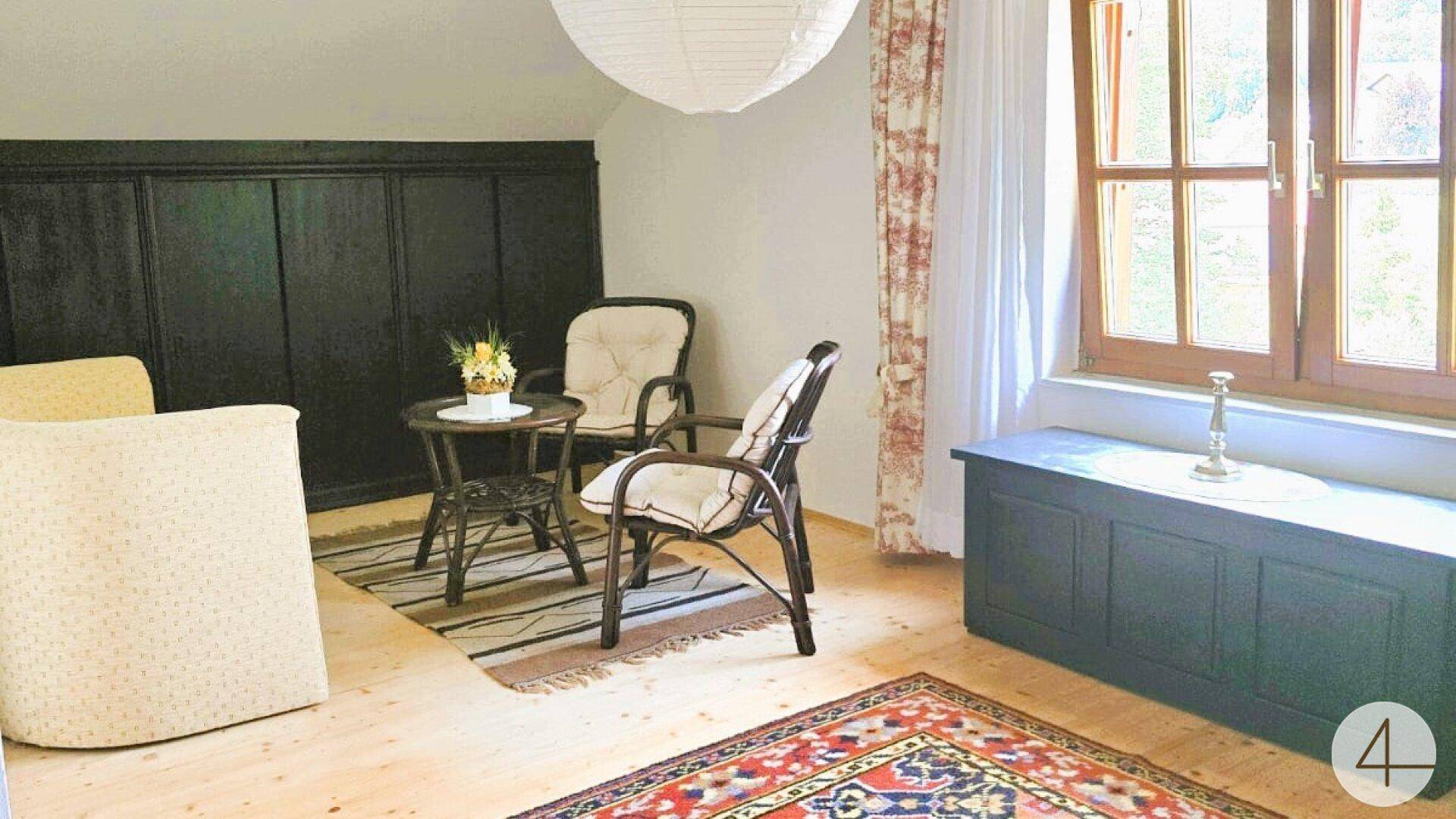 Heller Sitzbereich mit bequemen Sesseln, großem Fenster und integrierter Truhenbank.