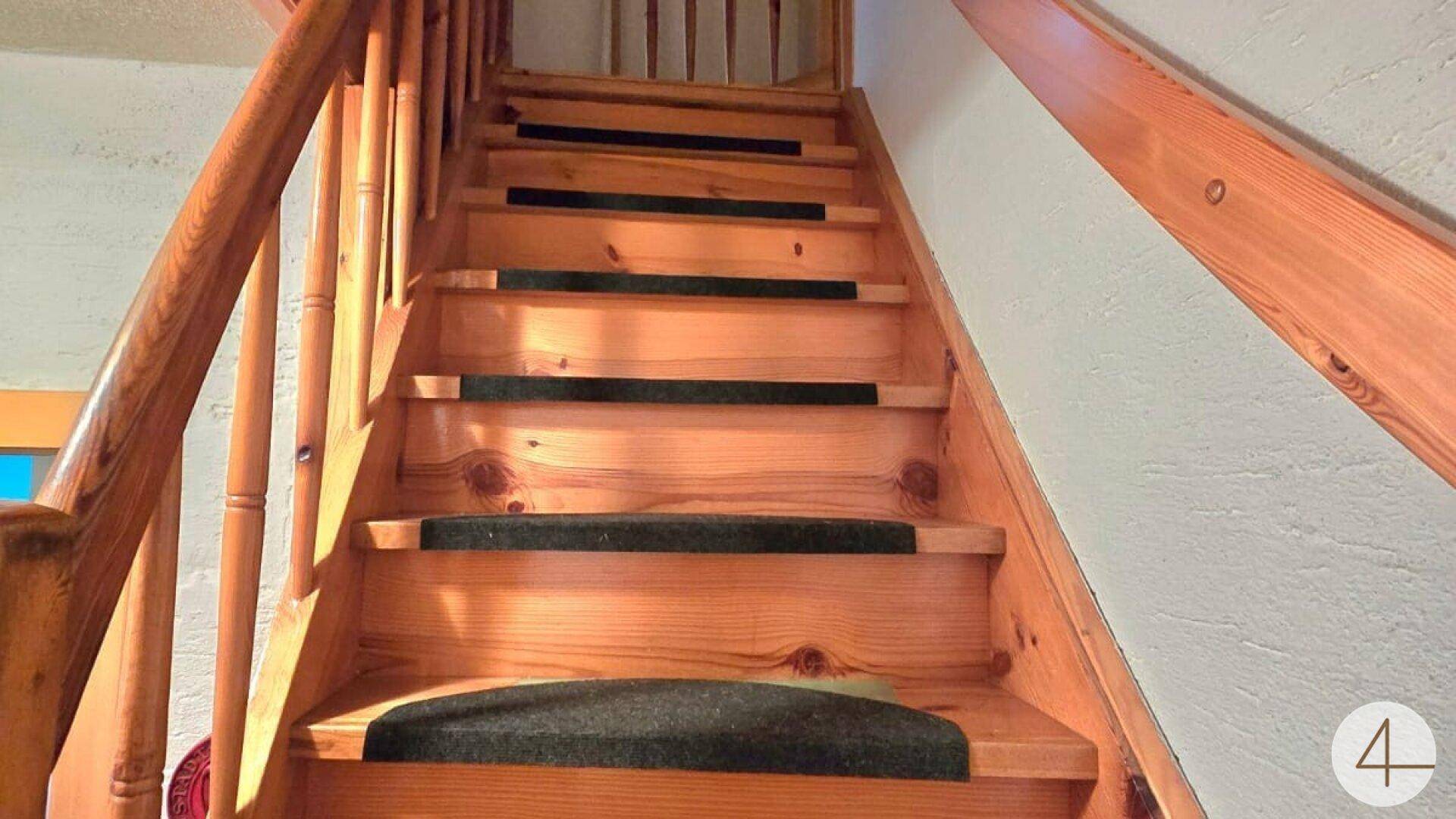 Robuste Holztreppe mit Teppichstufen, die die verschiedenen Etagen verbindet.