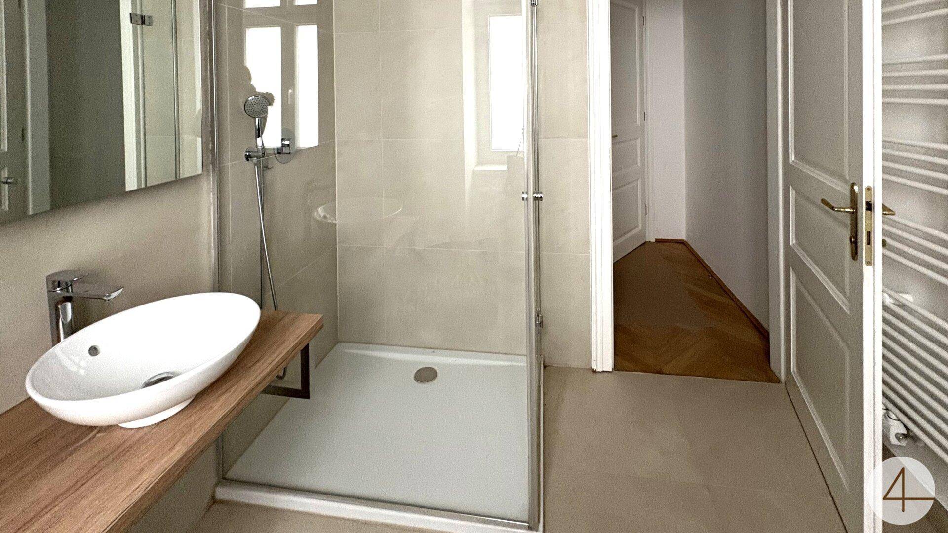 Modernes Badezimmer mit begehbarer Dusche, elegantem Waschbecken und Holzwaschtisch.