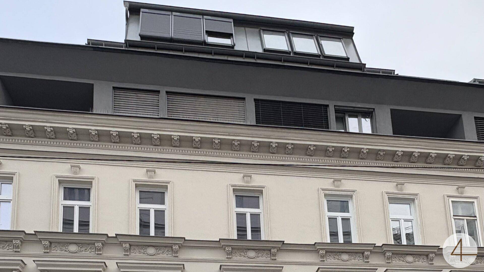 Kombination aus historischer Fassade und moderner Dachaufstockung mit großen Fenstern.