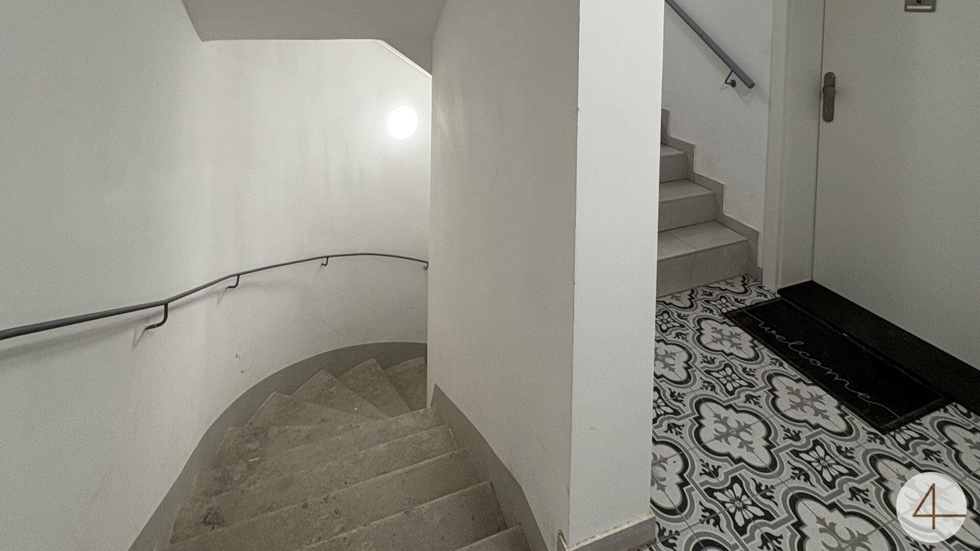 Historisches Treppenhaus mit geschwungener Treppe und dekorativem Fliesenboden im Eingangsbereich.