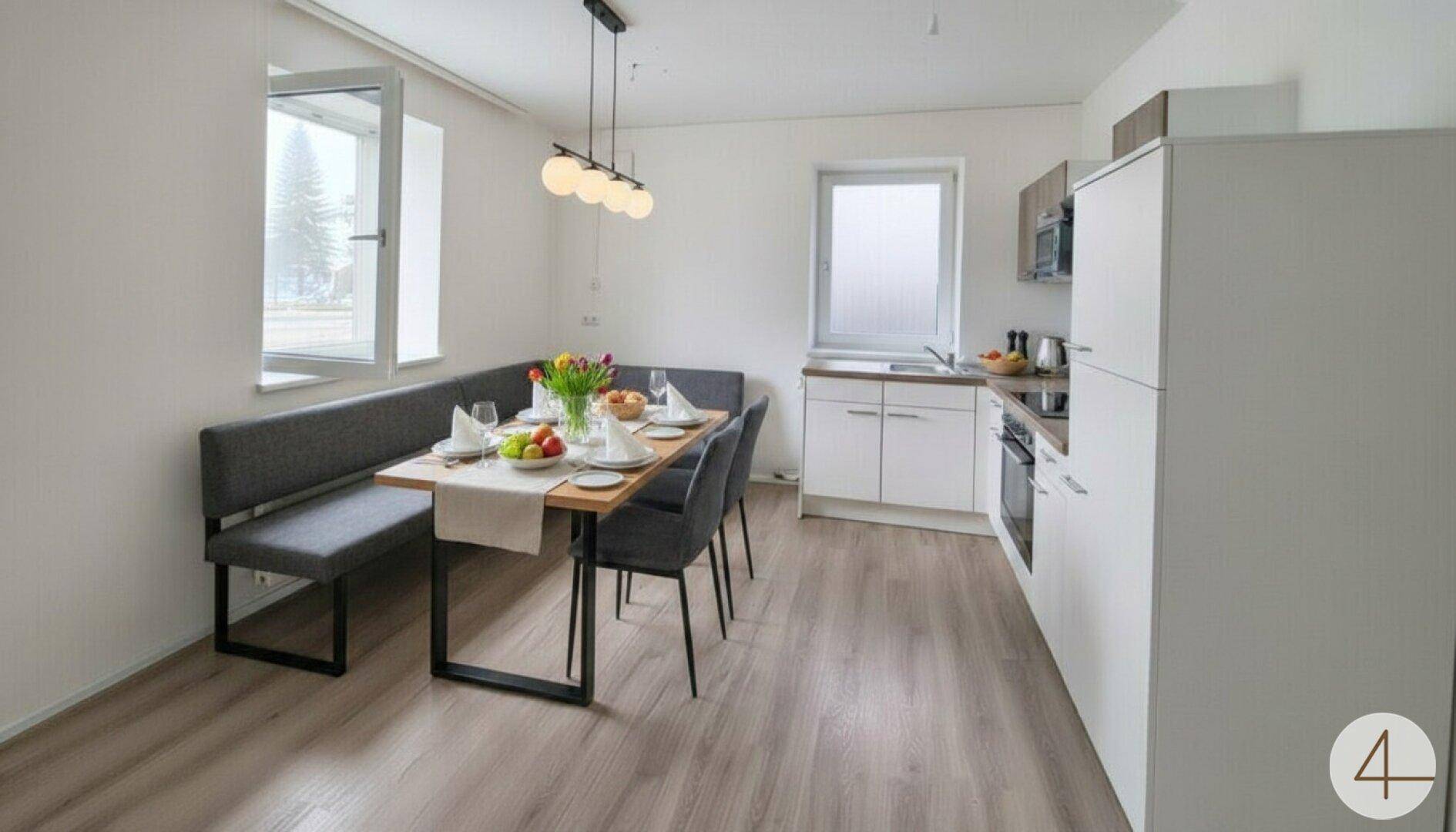 Moderne Wohnküche mit Essbereich, Einbauküche und hellem Laminatboden.