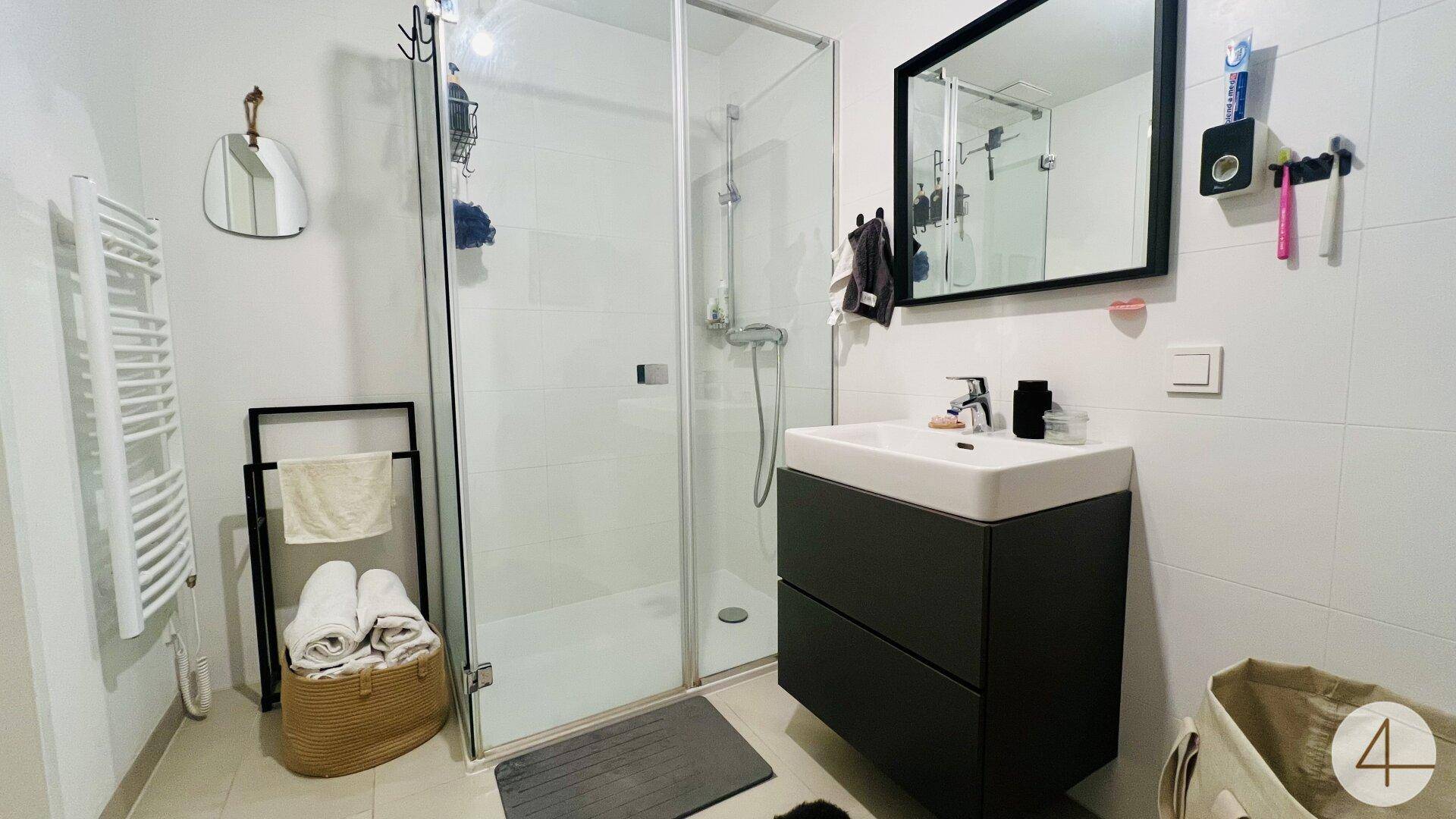 Modernes Badezimmer mit ebenerdiger Dusche, Waschtisch und beheiztem Handtuchhalter.