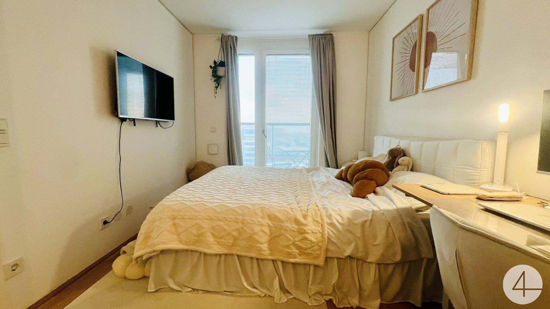 Helles Schlafzimmer mit großem Bett, Holzboden und Zugang zu einem Balkon.