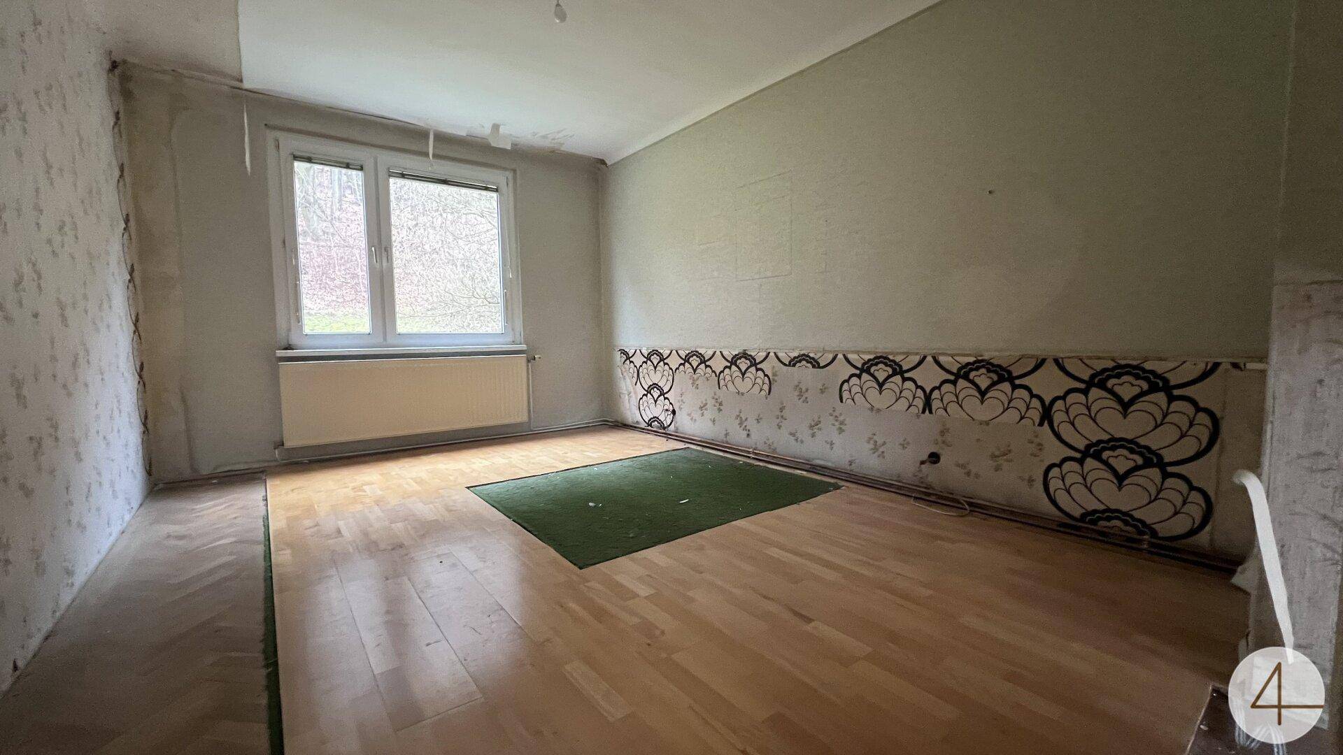 Schlafzimmer mit Holzboden, dekorativer Tapete und Fenster mit Blick ins Grüne.