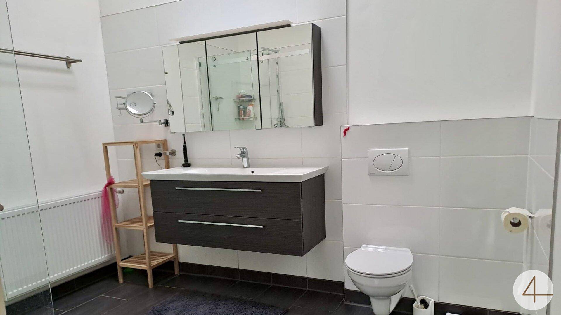 Modernes Badezimmer mit Hängewaschbecken, Spiegelschrank und Wand-WC.
