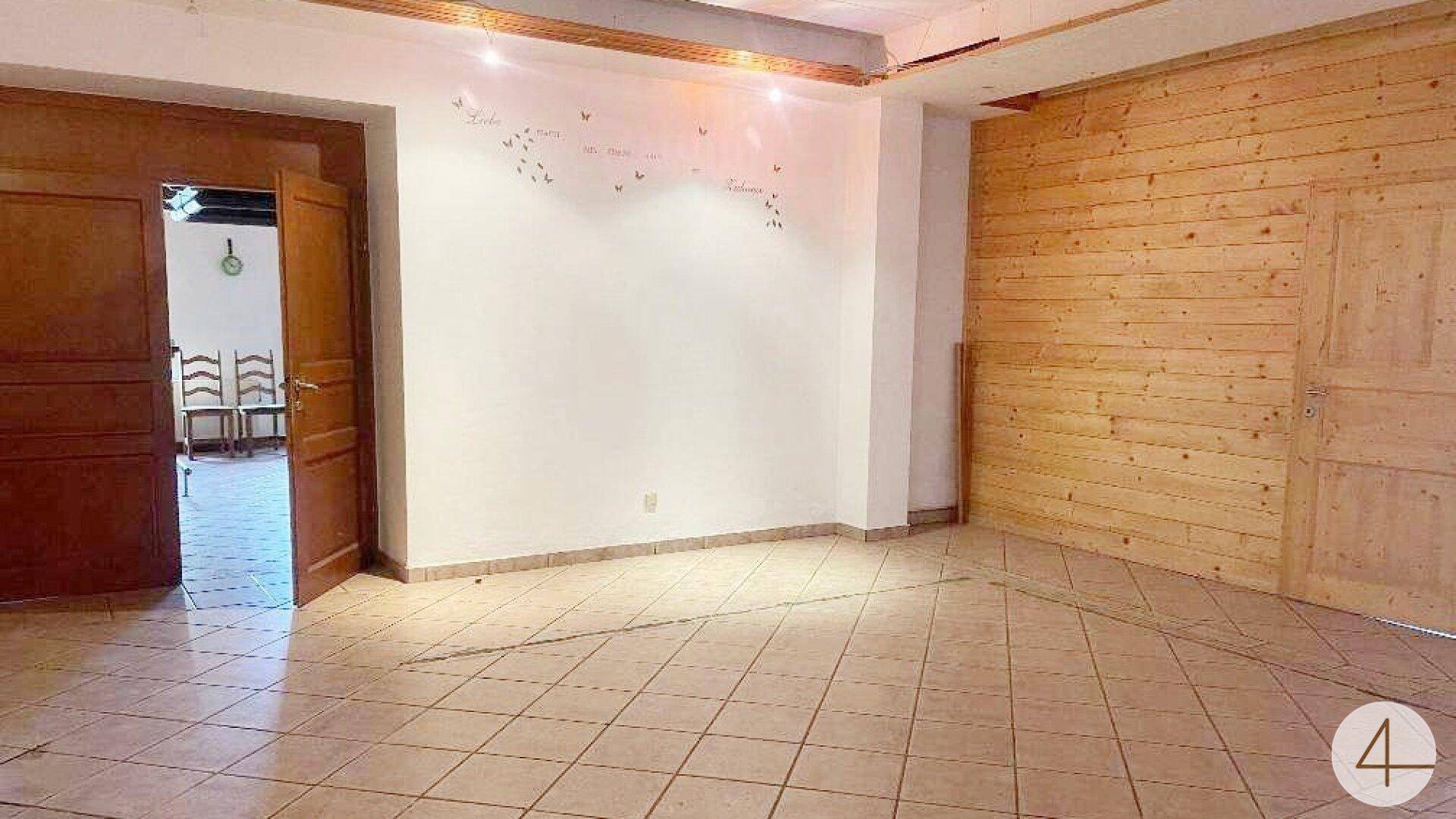 Geräumiger, leerer Wohnbereich mit Holzwand, weißen Wänden und hellen Fliesen.