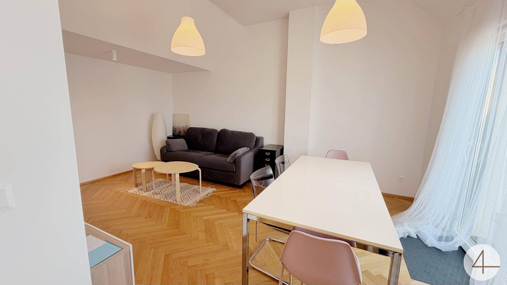 Offener Wohn- und Essbereich mit Parkettboden, Sofa und großem Fenster.