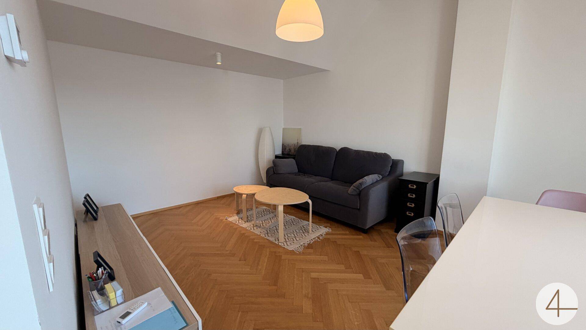 Geräumiger Wohnbereich mit bequemer Couch, Couchtischen und hellem Parkettboden.