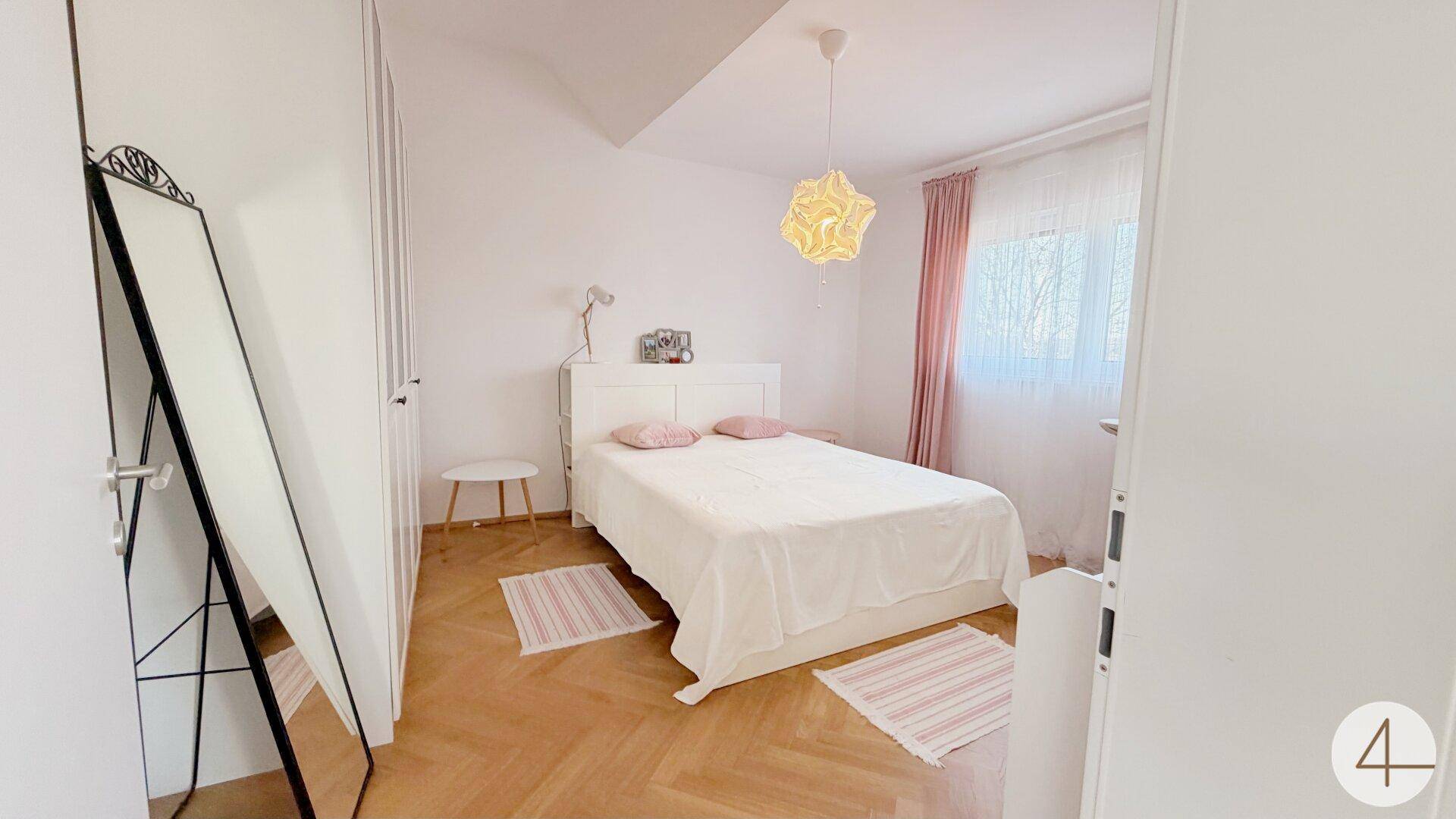 Helles Schlafzimmer mit Parkettboden, Dachschräge und einem großen Spiegel.