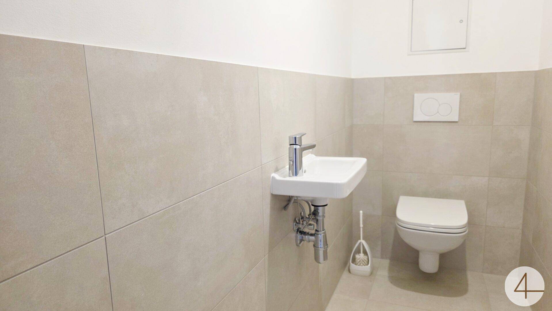Kleines Gäste-WC mit wandhängender Toilette und modernem Waschbecken.