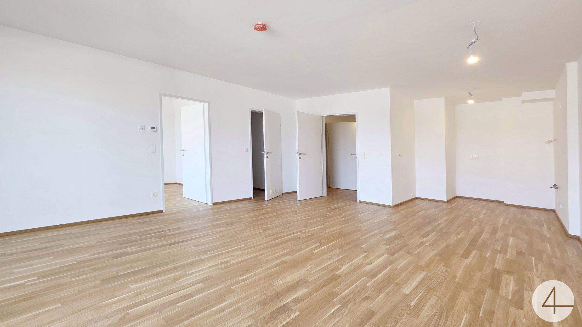 Geräumiges, helles Wohnzimmer mit Parkettboden und mehreren Türen zu angrenzenden Räumen.