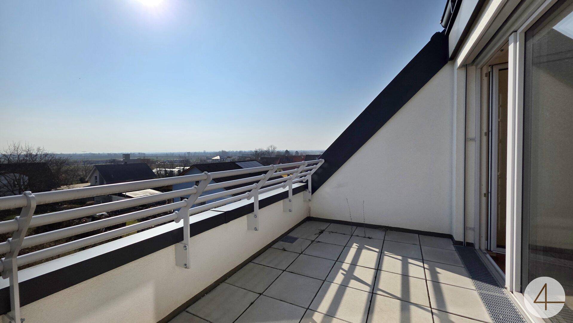 Geräumiger Balkon mit Fliesenboden, Metallgeländer und weitem Blick über die Landschaft.