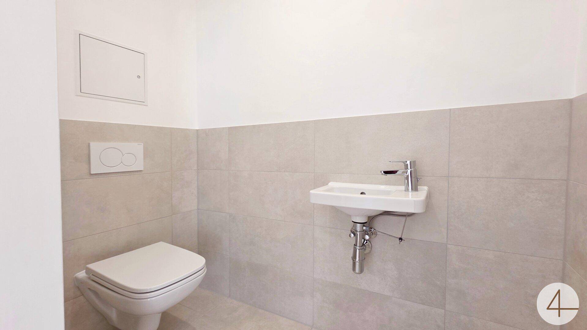 Helles Gäste-WC mit wandhängender Toilette, kleinem Waschbecken und modernen Fliesen.
