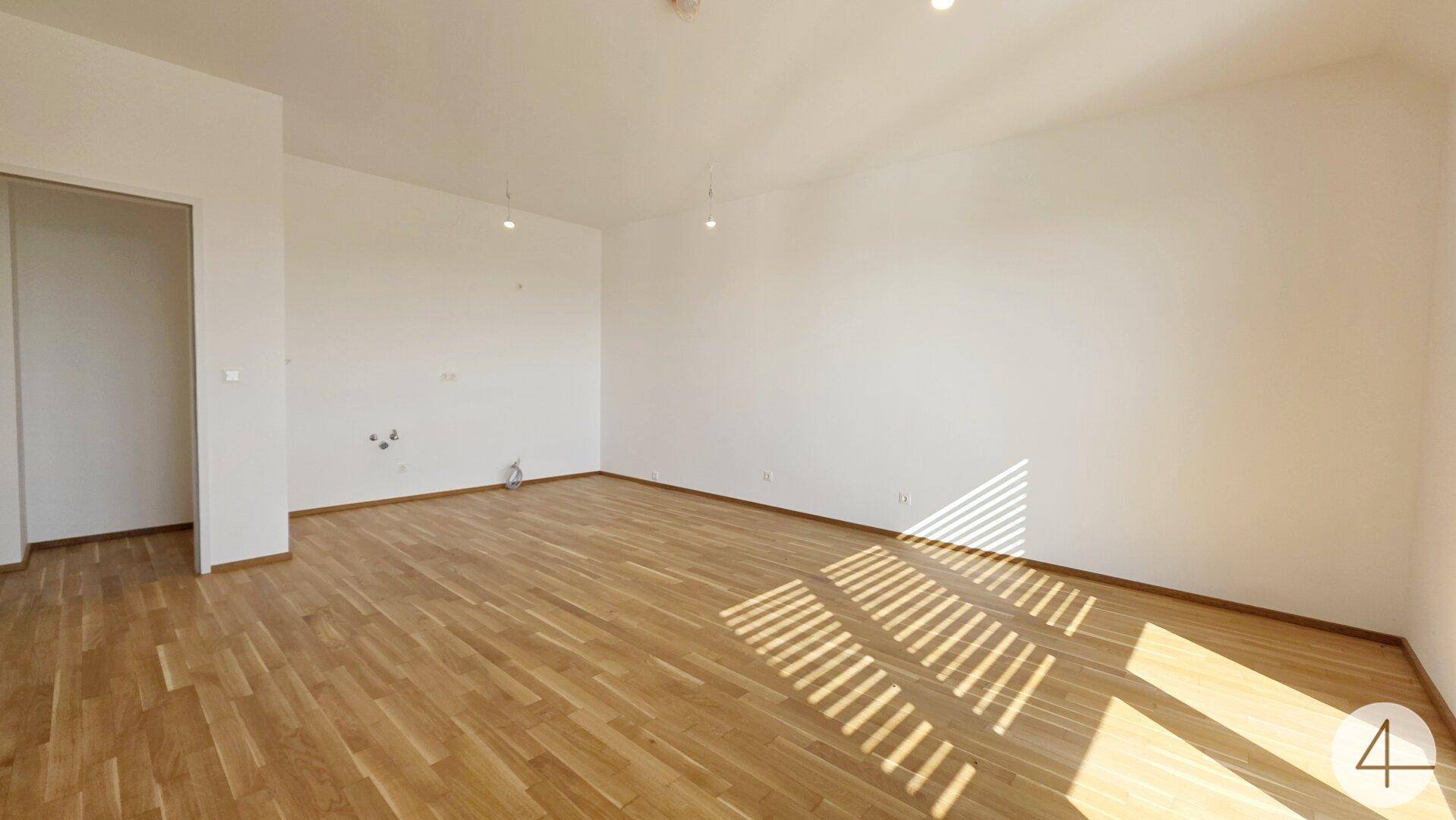 Helles Wohnzimmer mit Parkettboden, das von der Morgensonne durchflutet wird und ein warmes Ambiente schafft.