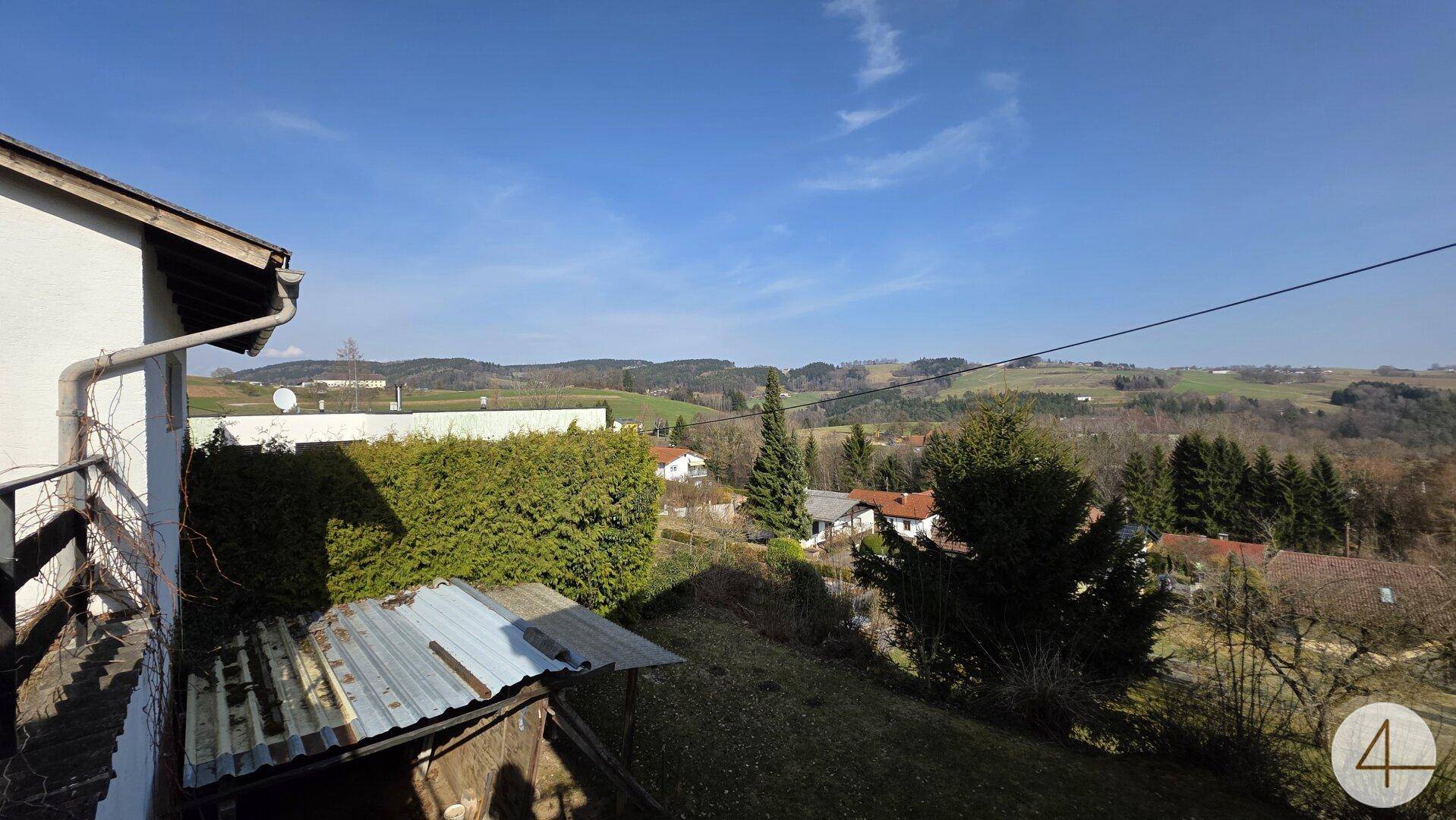 Panoramablick auf die weite, grüne Hügellandschaft unter einem klaren blauen Himmel.