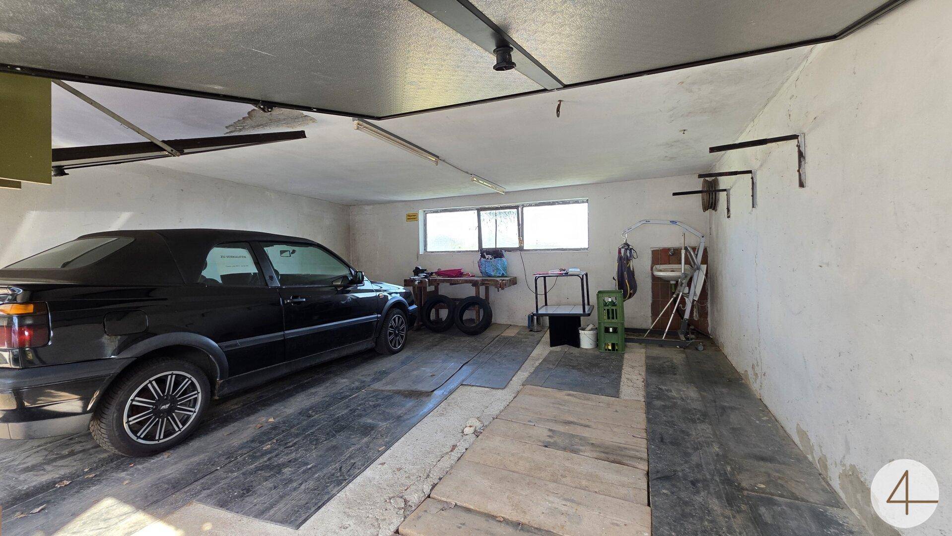 Geräumige Garage mit einem geparkten Auto und Fenstern für Tageslicht.